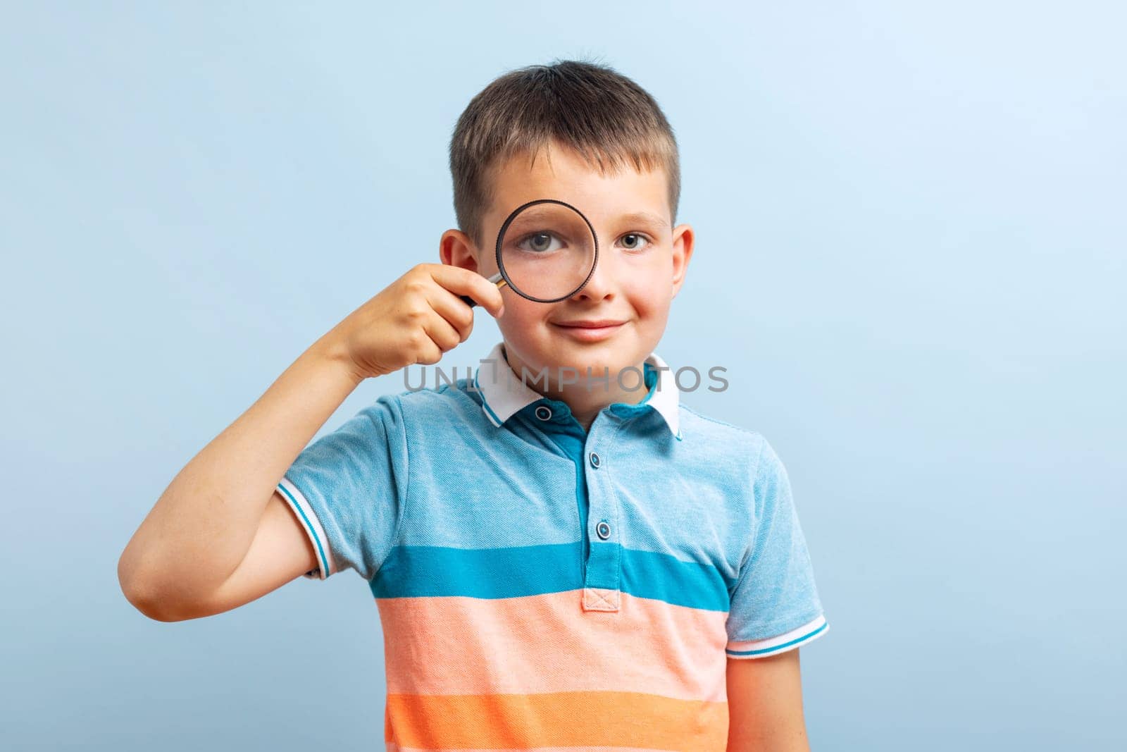 Schoolboy in casual clothes looks through magnifying glass by andreyz