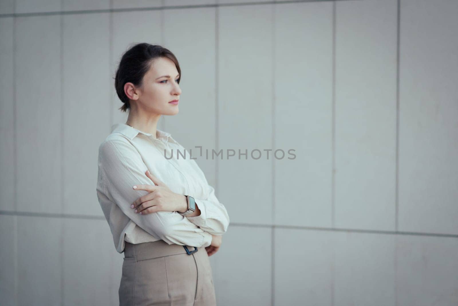 Portrait of young caucasian serious bisiness woman looking into the distance with crossed arms with copy space.