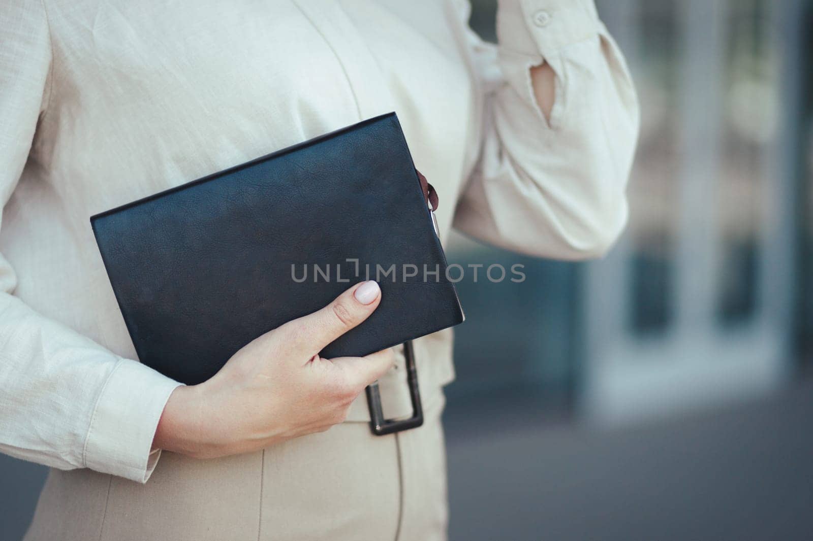 Close-up on a notebook in the hands of a young successful business woman against the backdrop of a business center.