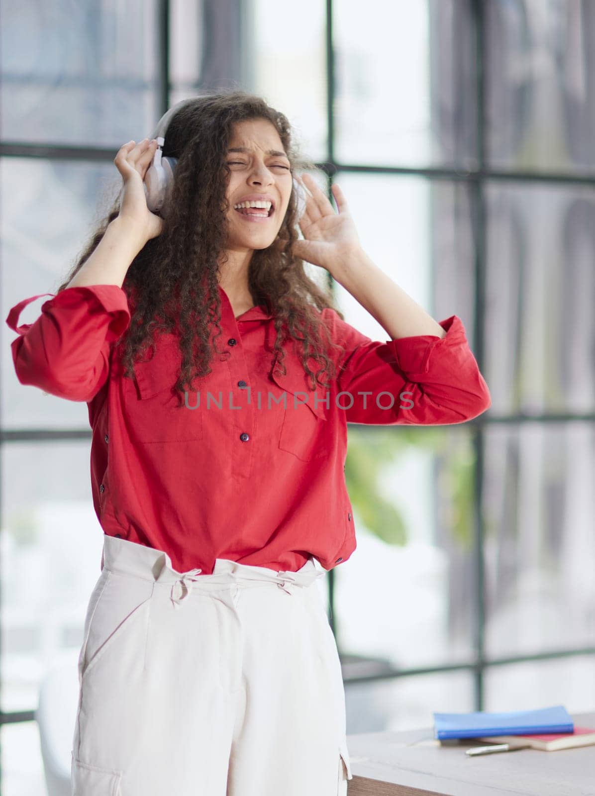 Beautiful smiling young woman in headphones in modern office by Prosto