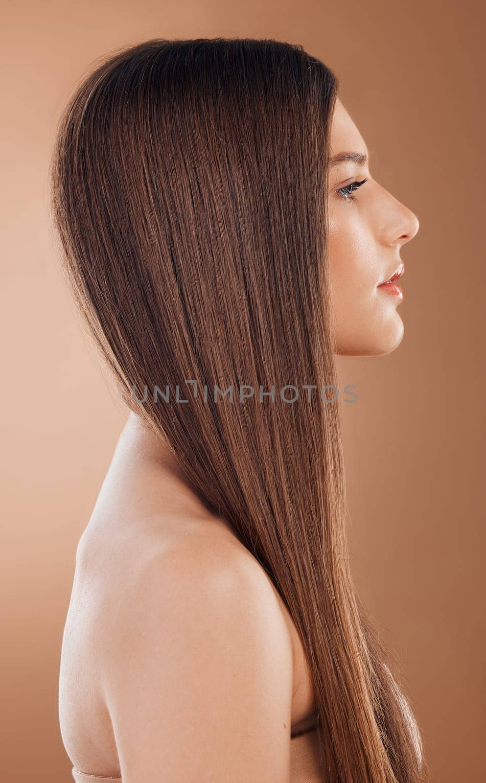 Woman, beauty and hair care in studio for shine, glow and keratin treatment, texture or color on brown background. Model profile, hair style and cosmetics, beauty salon and shampoo product for growth.