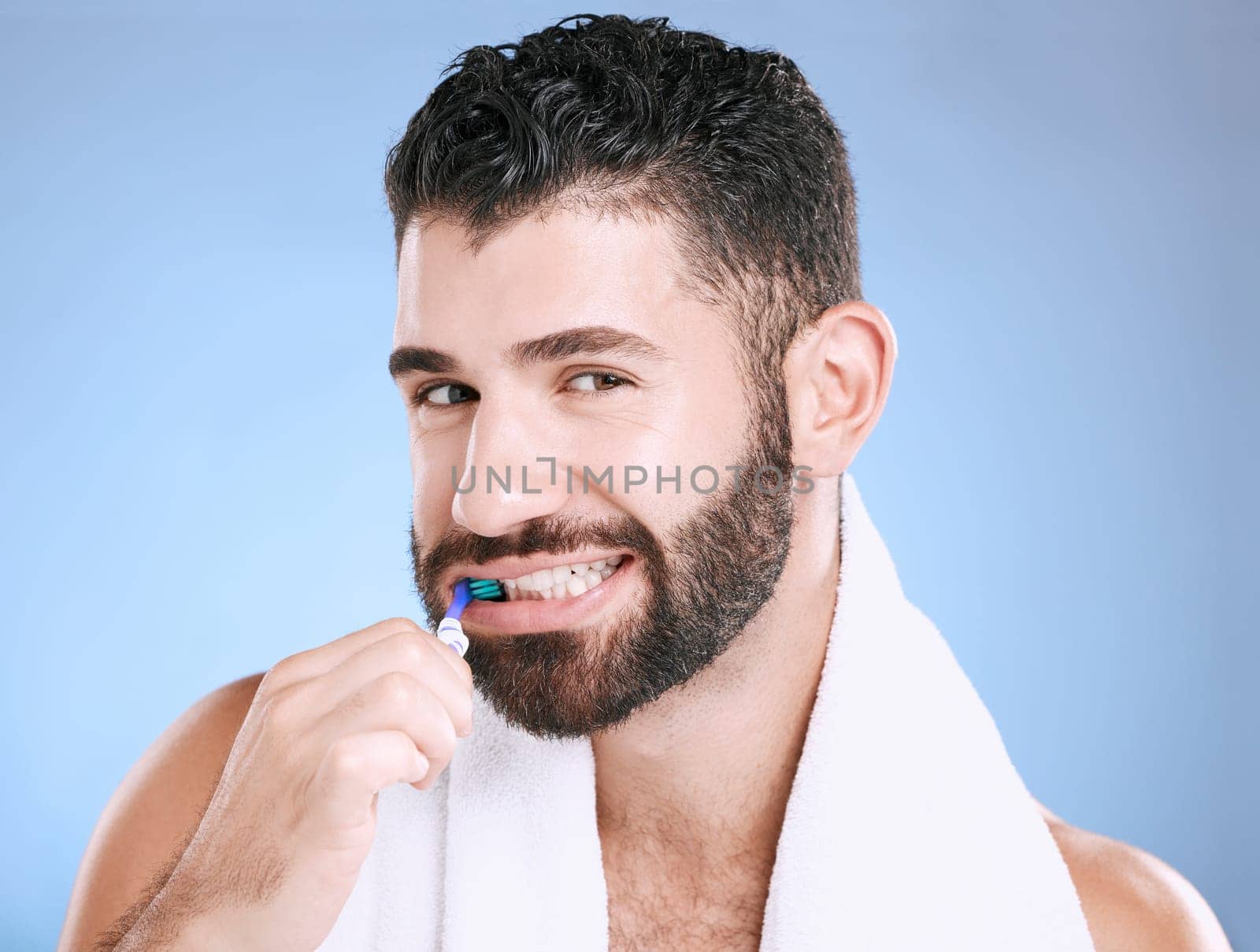 Studio portrait, man and toothbrush for teeth, dental wellness and healthy smile, mouth and cleaning. Happy male model, oral care and fresh breath for gums, dentistry and hygiene on blue background by YuriArcurs