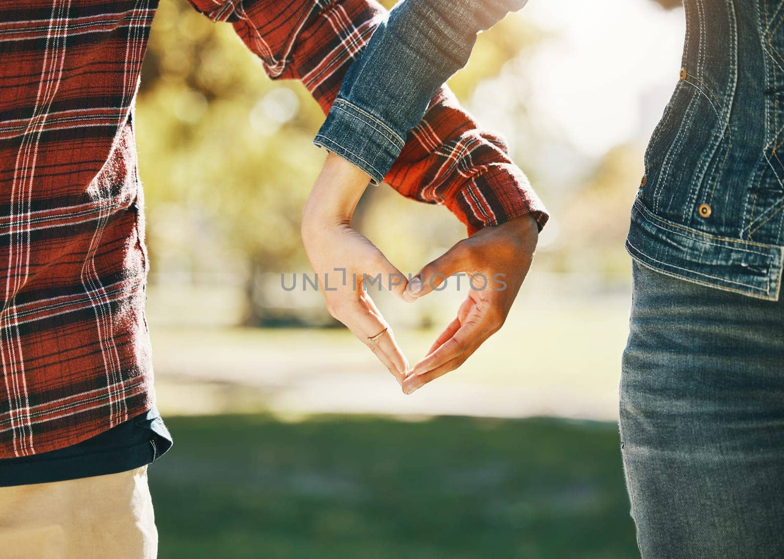 Love, interracial and hands of a couple in a heart for support, diversity and trust in nature. Emoji, marriage and gesture from a man and woman with emotion, romance and affection on valentines day.