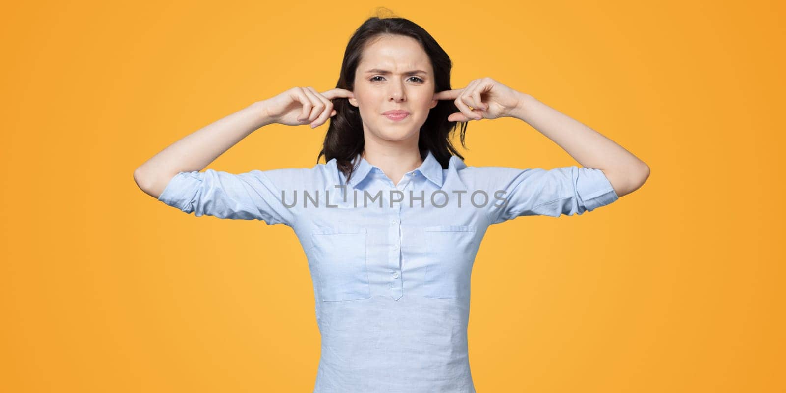long-haired beautiful young brunette woman covering her ears with her hands by Fabrikasimf