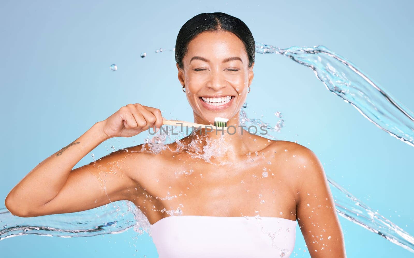Bamboo toothbrush of black woman isolated on blue background with toothpaste, water splash and dental health. Model or person brushing teeth with eco friendly and sustainable product in studio mockup.