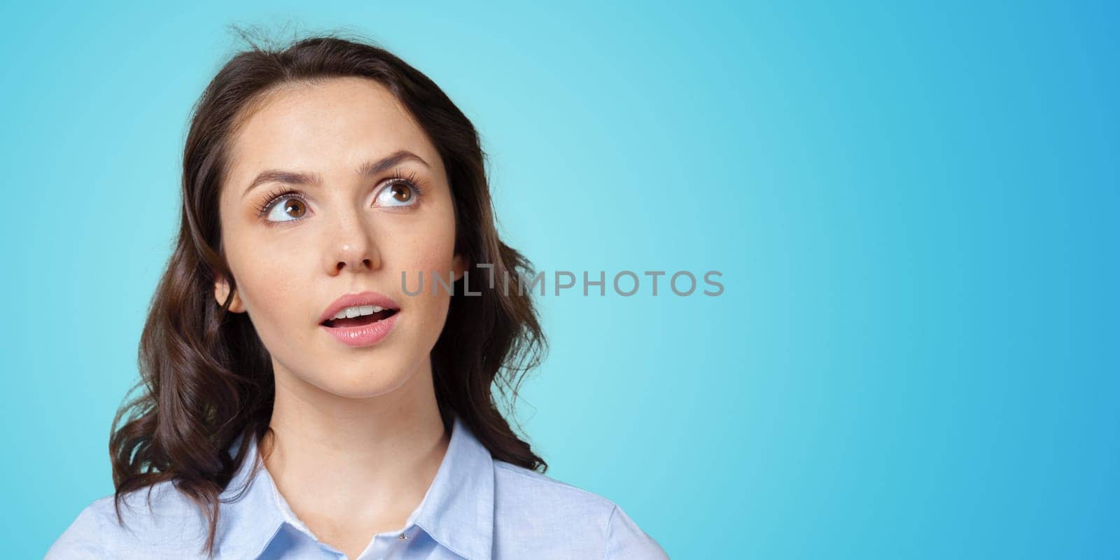 Thoughtful business woman looking up isolated on blue