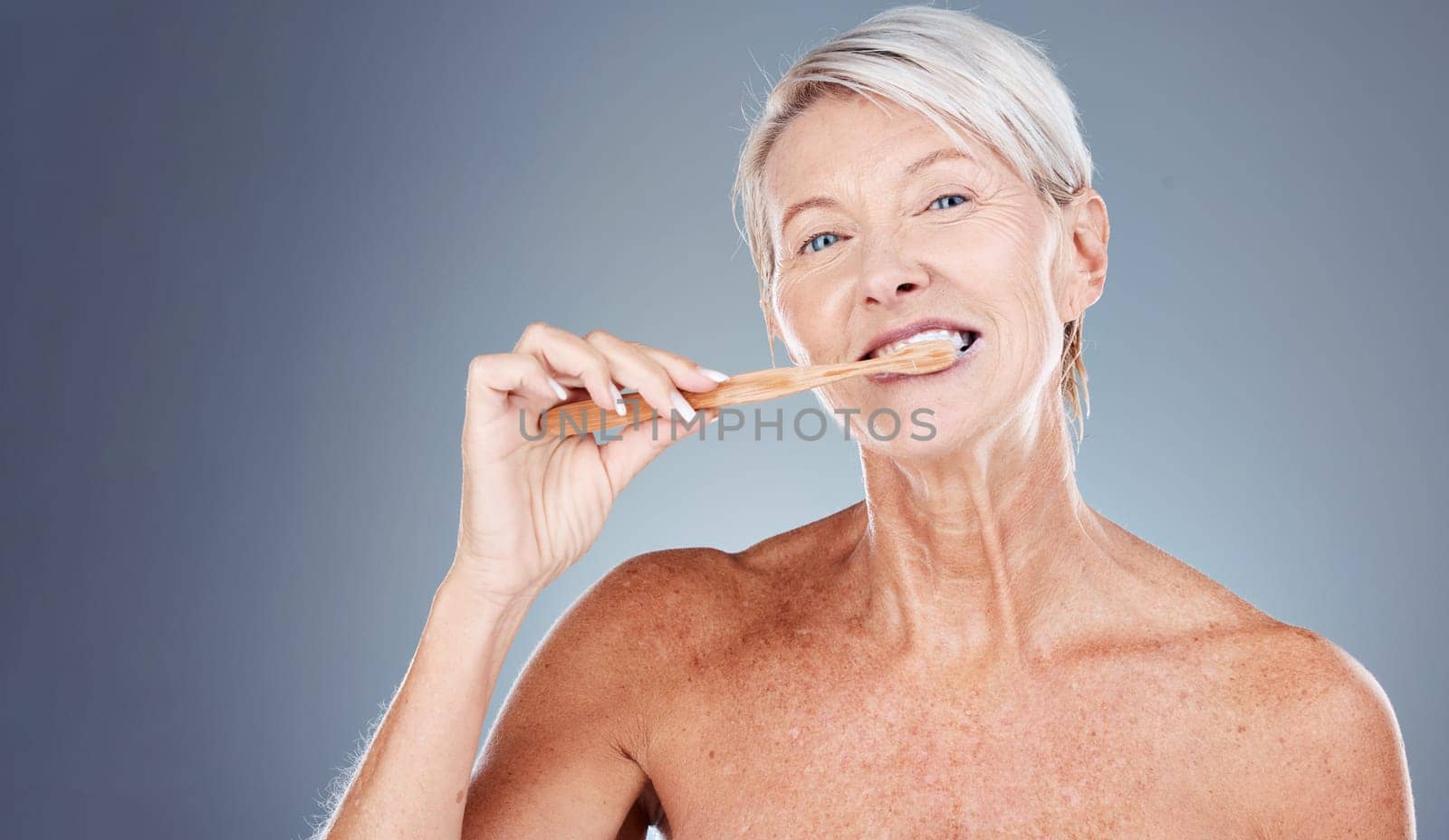 Brushing teeth, portrait and senior woman in studio for dental, mouth and tooth wellness with product marketing, advertising and promotion space. Elderly model with toothbrush for morning care mockup by YuriArcurs