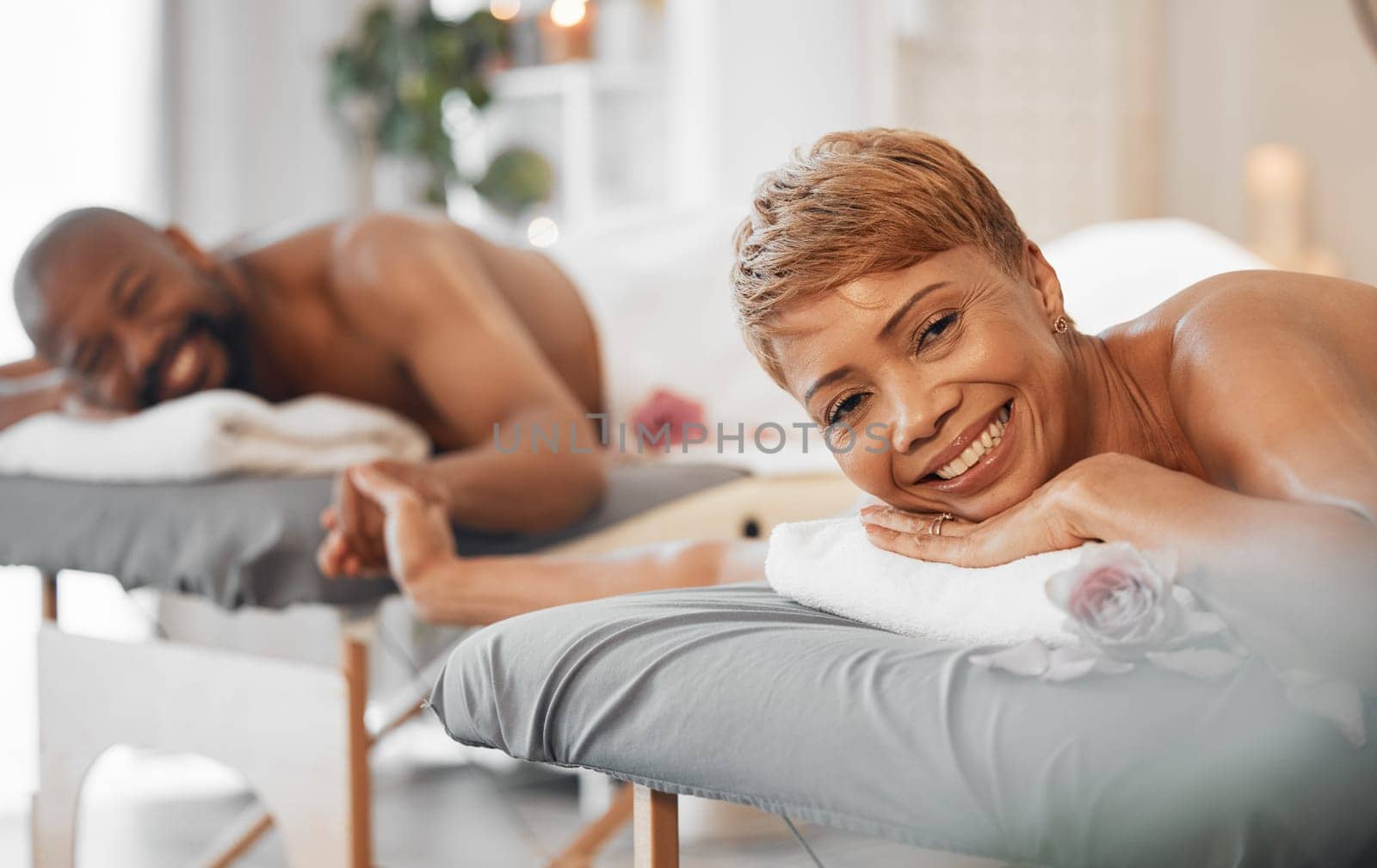 Love, massage and couple holding hands at a spa in celebration of a happy marriage anniversary holiday. Smile, romance and relaxed black woman with a happy romantic African partner at a luxury resort.
