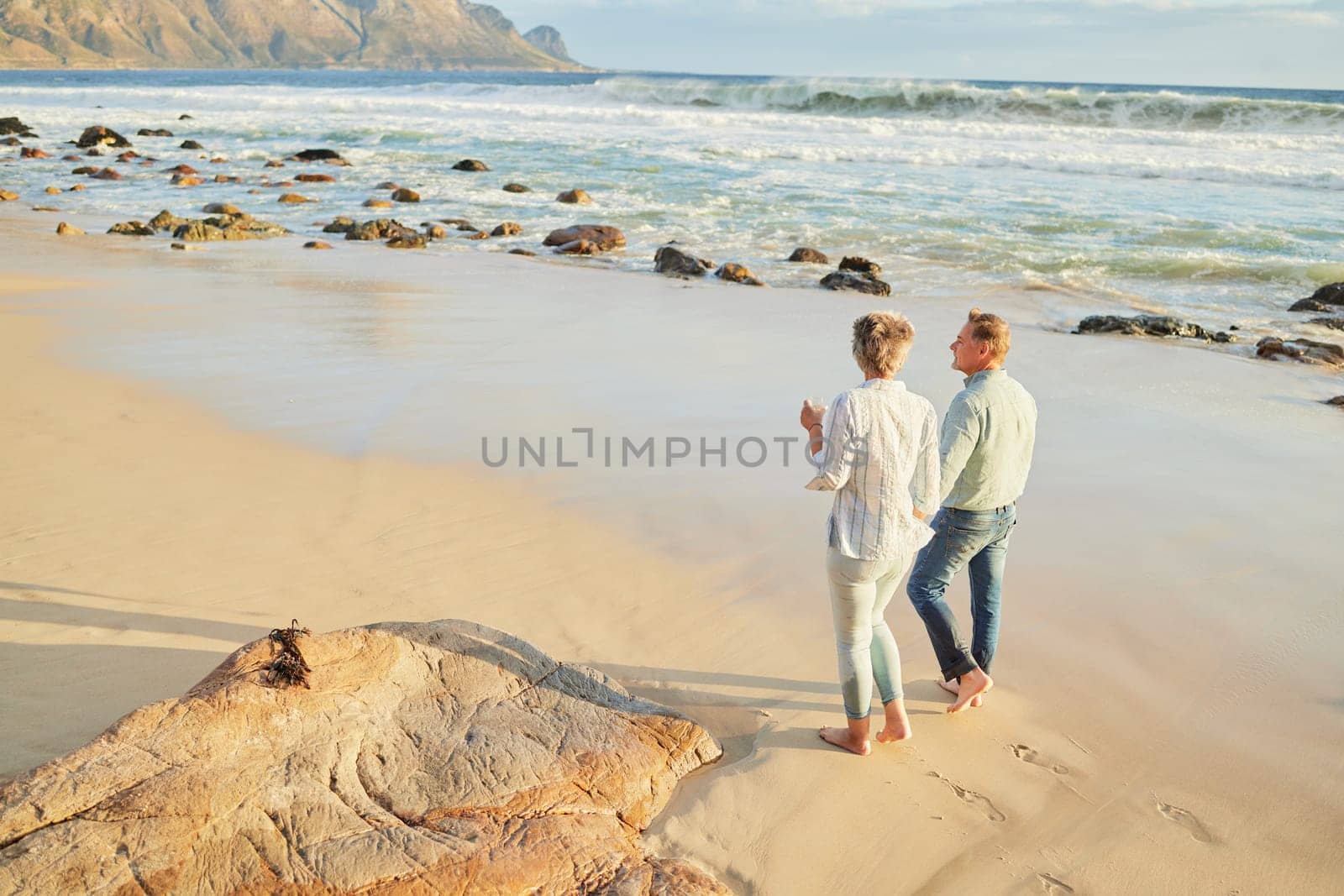 Beach, love and a senior couple walking on the sand by the ocean or sea for romance or dating at sunset. Nature, summer or back with a mature woman and man taking romantic walk together on the coast.