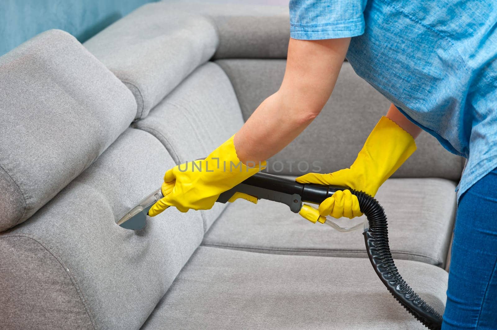Cleaning concept. Woman washes soft furniture in living room. Employee removing dirt from furniture, closeup