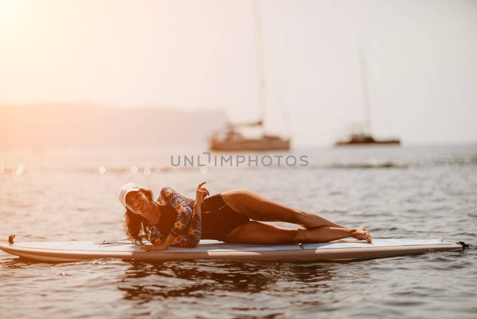 Woman sup yoga. Middle age sporty woman practising yoga pilates on paddle sup surfboard. Female stretching doing workout on sea water. Modern individual hipster outdoor summer sport activity