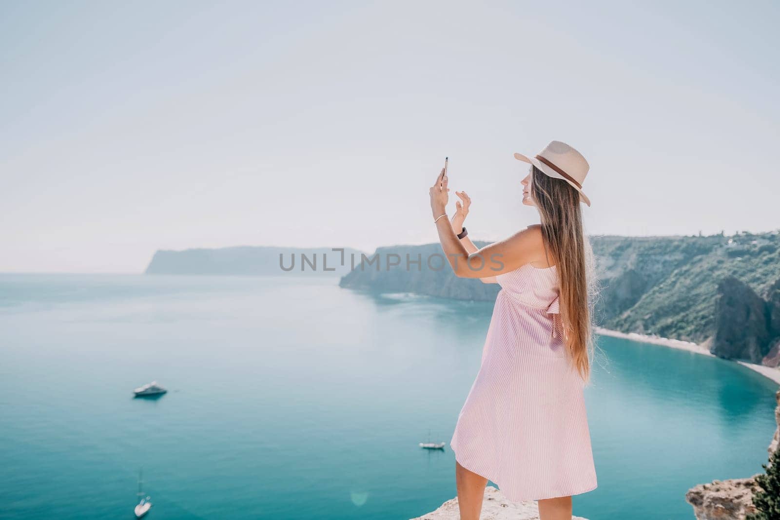 Woman sea laptop. Business woman in yellow hat freelancer with laptop working over blue sea beach. Girl relieves stress from work. Freelance, digital nomad, travel and holidays concept by panophotograph