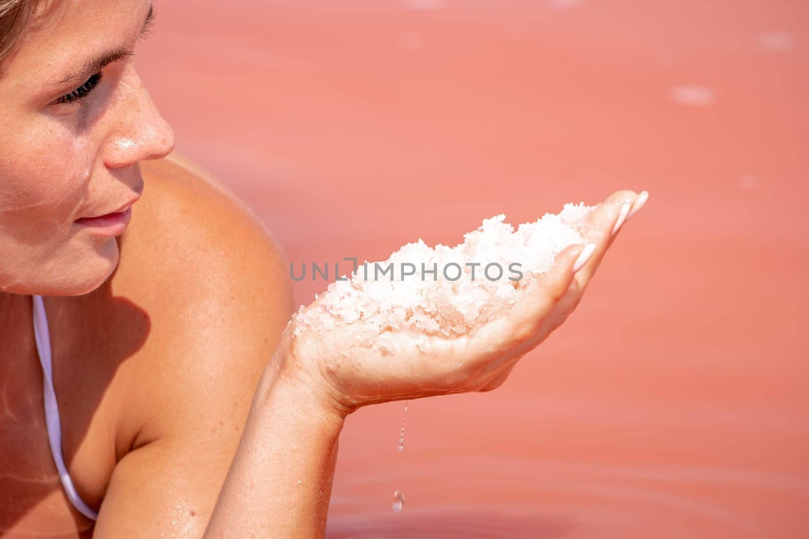 Young woman with long hair in pink salty lake with crystals of salt. Extremely salty pink lake, colored by microalgae with crystalline salt depositions. Spa, beauty and health care concept. by panophotograph