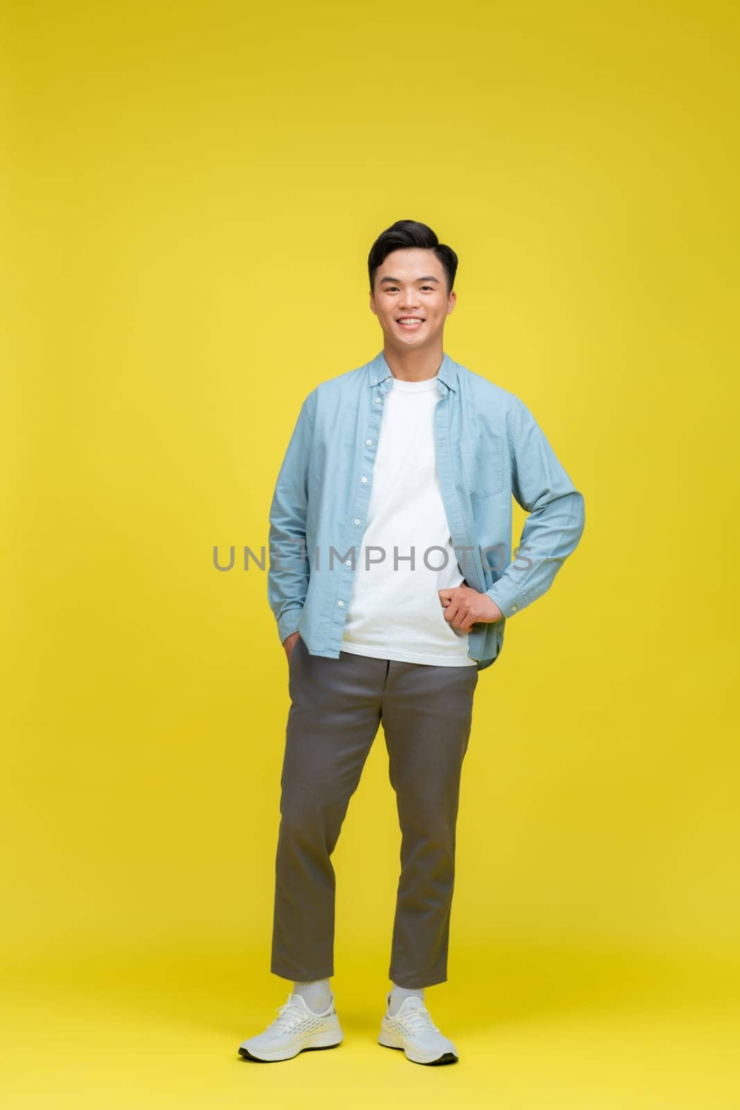 Funny young handsome man smiling on yellow background with copy space by makidotvn