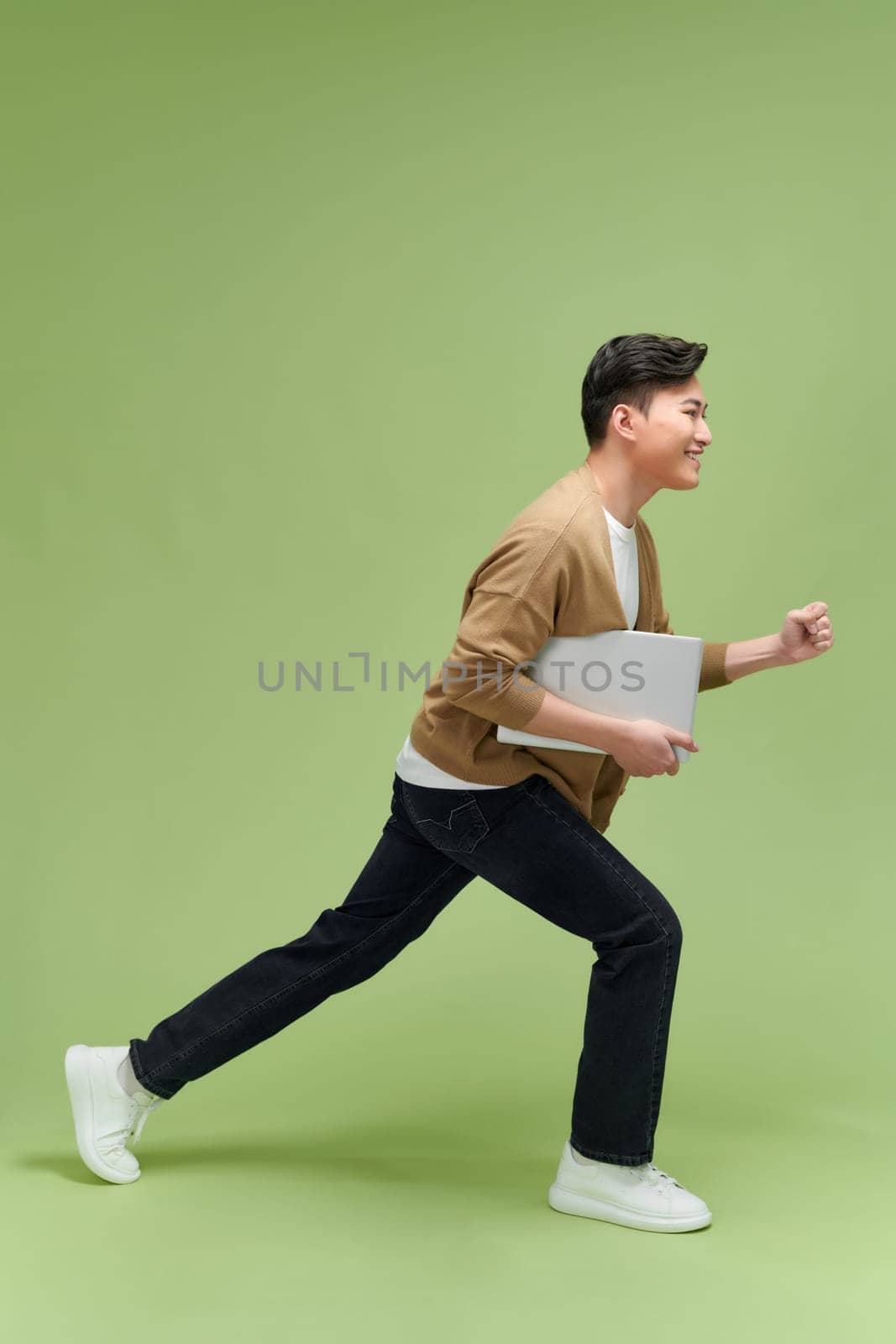 Full length image of young Asian businessman on green background