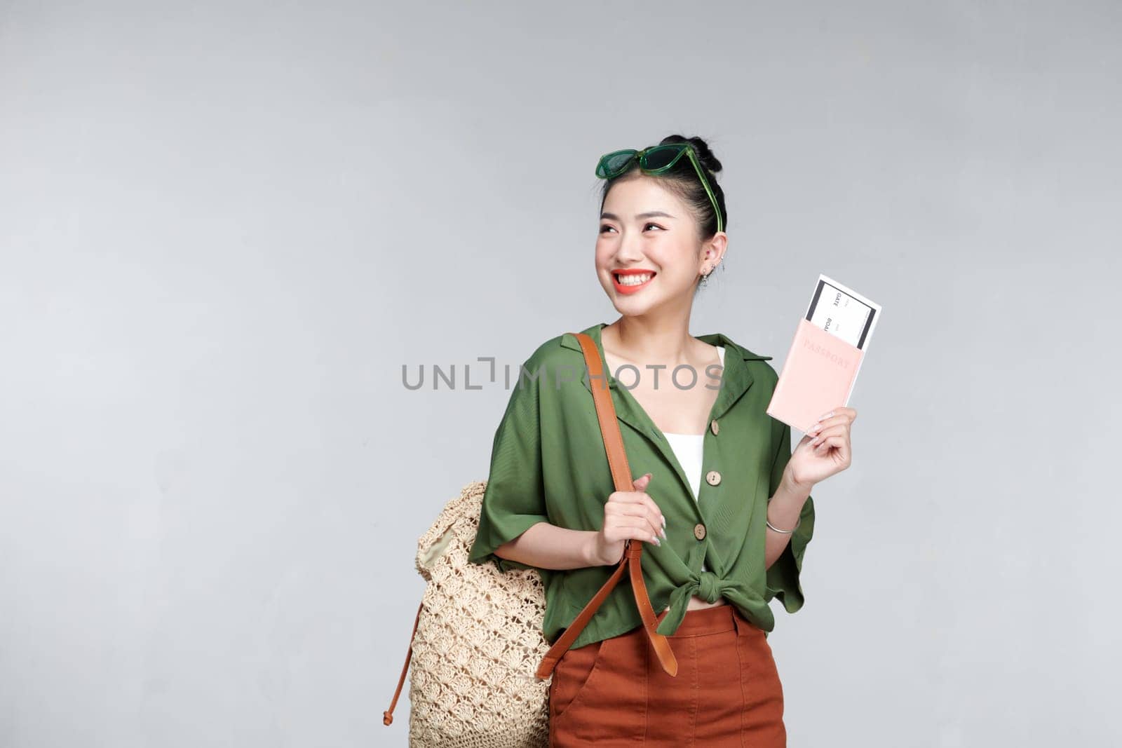 Young woman traveler with backpack and passport with ticket isolated on white