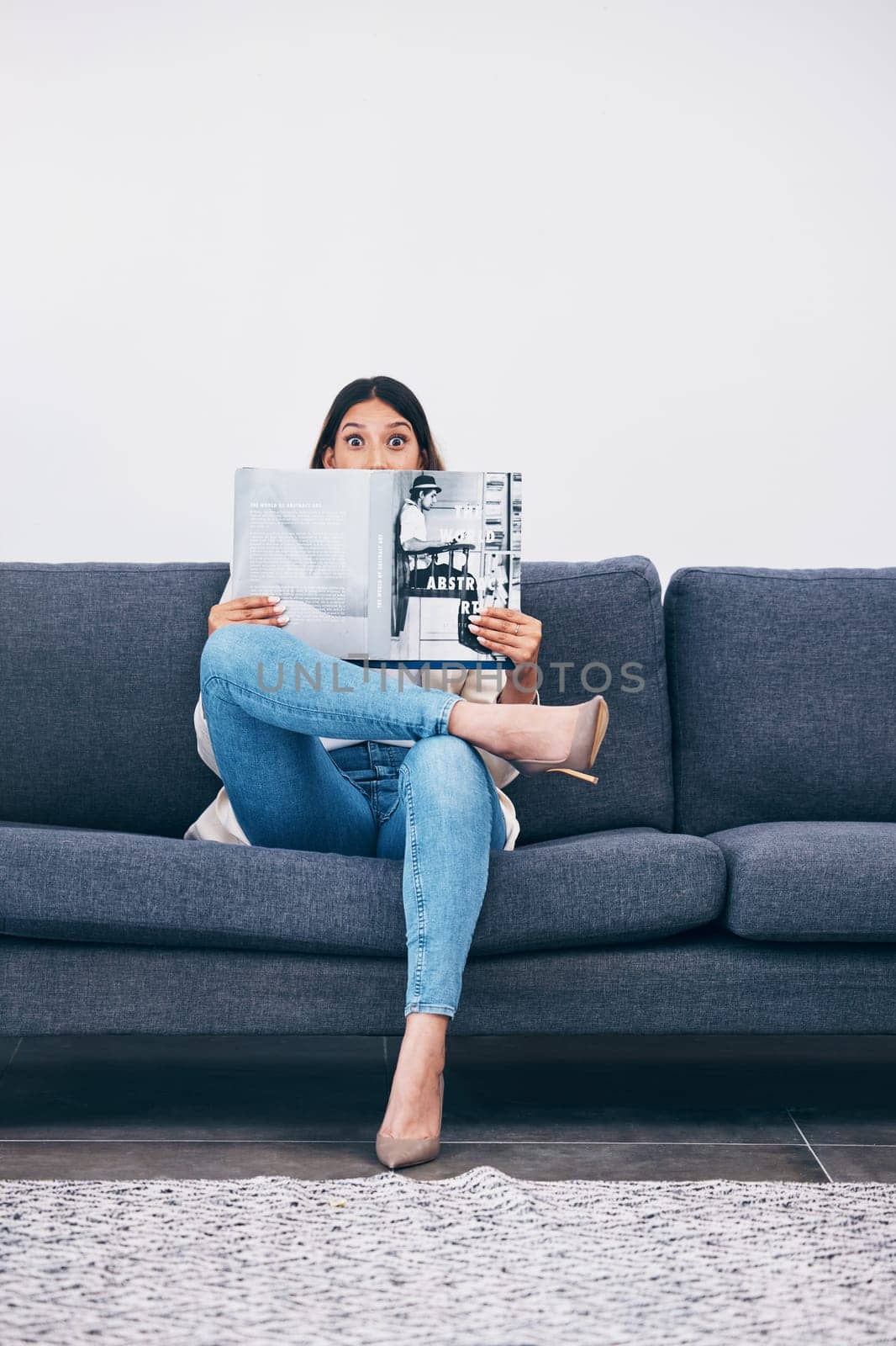 Wow, magazine or woman reading newspaper articles for trendy information on house sofa with wall mockup. Story, surprised or shocked person studying abstract art for knowledge or press announcement by YuriArcurs