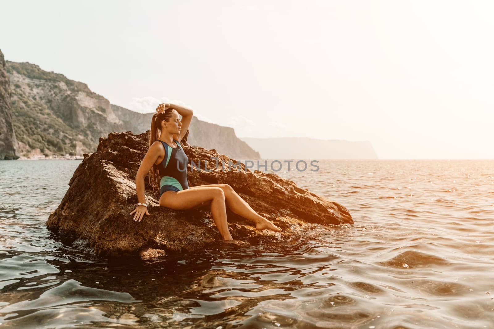 Woman travel summer sea. A happy tourist in a blue bikini enjoying the scenic view of the sea and volcanic mountains while taking pictures to capture the memories of her travel adventure. by Matiunina