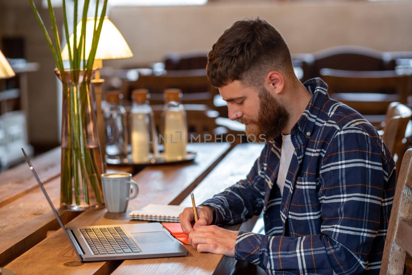 Casual business man or freelancer planning his work on notebook, working on laptop computer with smart phone, cup of coffee on table at coffee shop or home office. by nazarovsergey