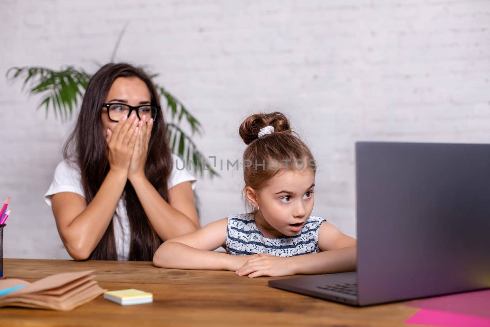 A young mother with little daughter are shopping on the Internet at personal computer. Online Family Shopping Concept