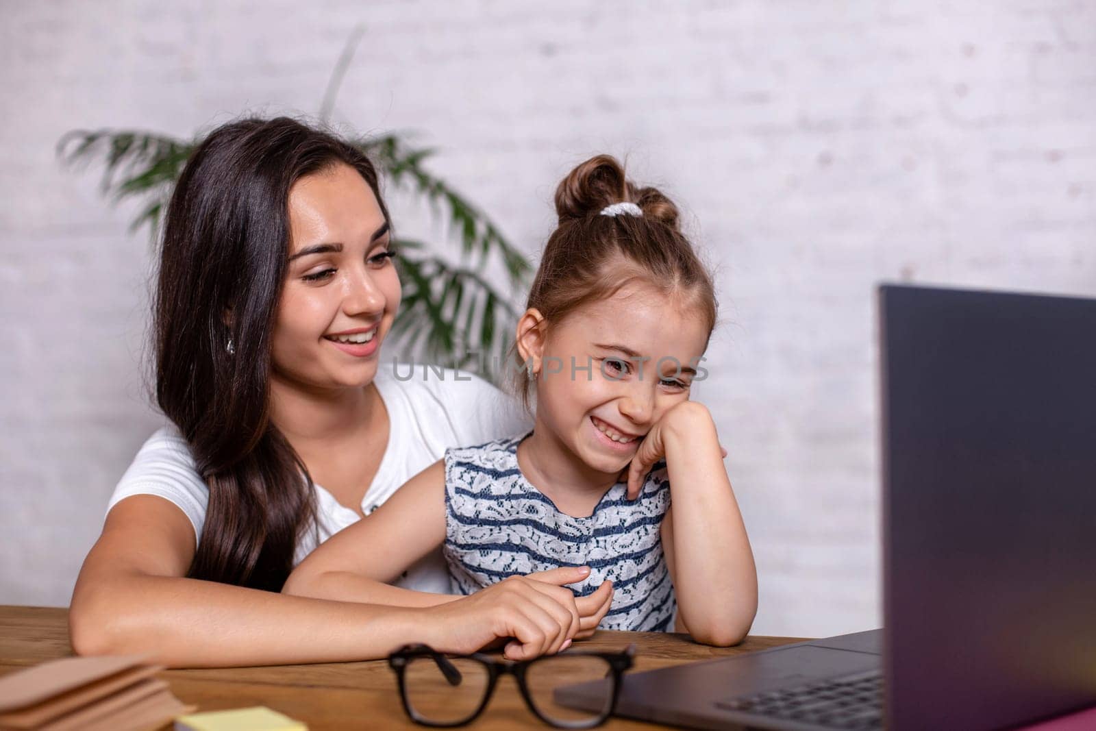 A young mother with little daughter are shopping on the Internet at personal computer. Online Family Shopping Concept