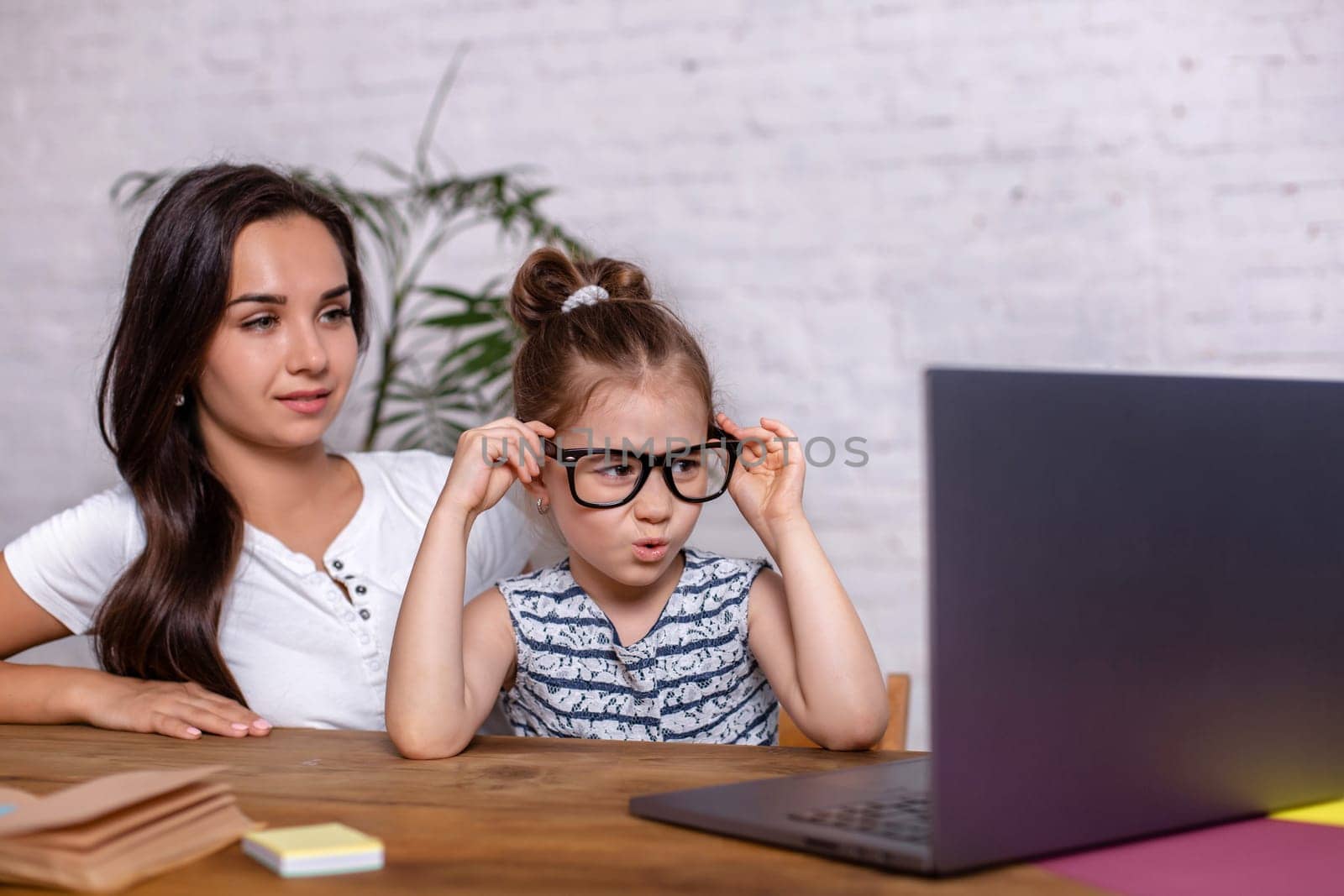 A young mother with little daughter are shopping on the Internet at personal computer by nazarovsergey