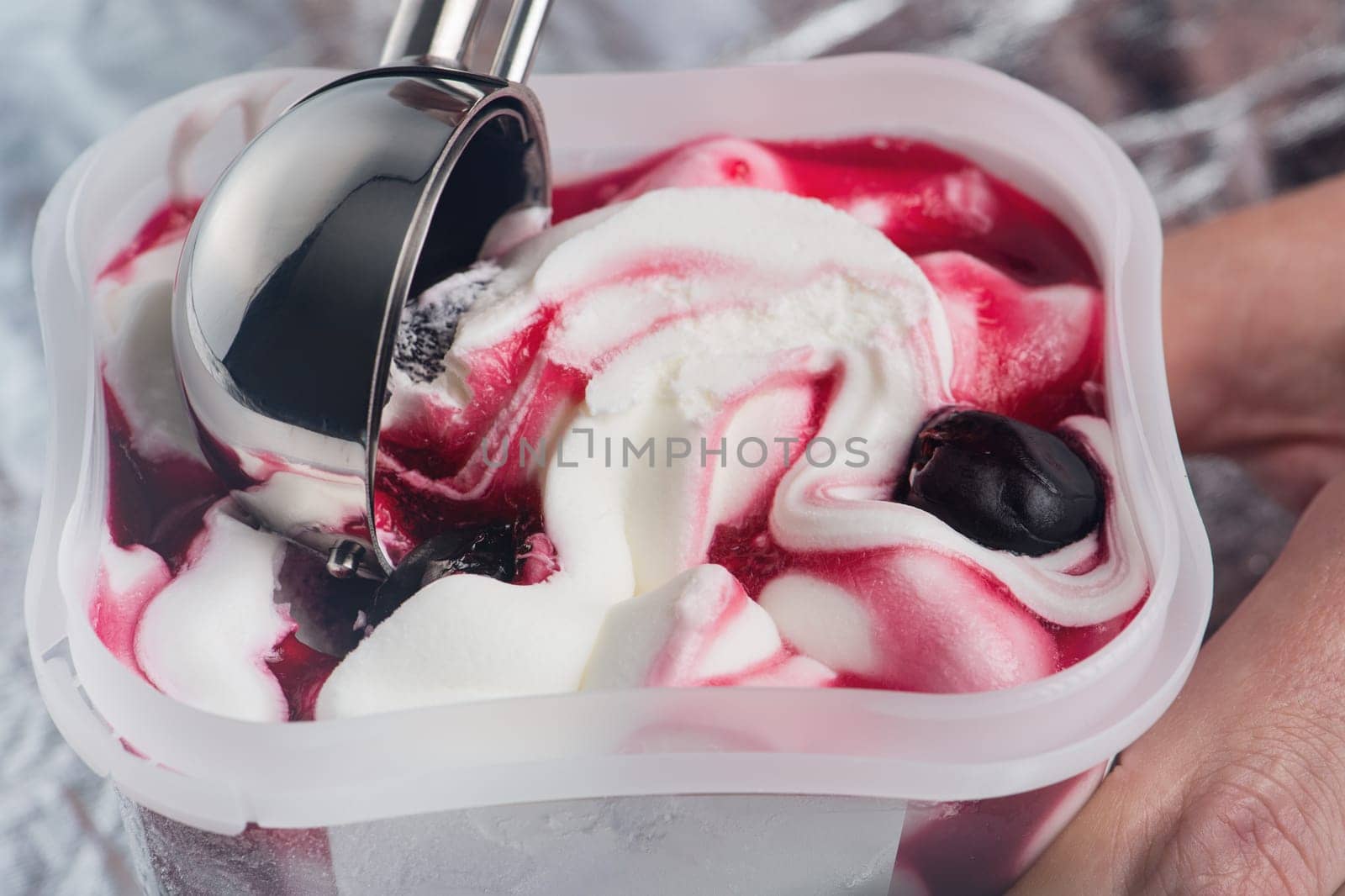 Cherry ice cream. An ice cream spoon is inserted into an ice cream with a cherry in a cup. Ice cream closeup. The concept of treats for children and adults. by SERSOL