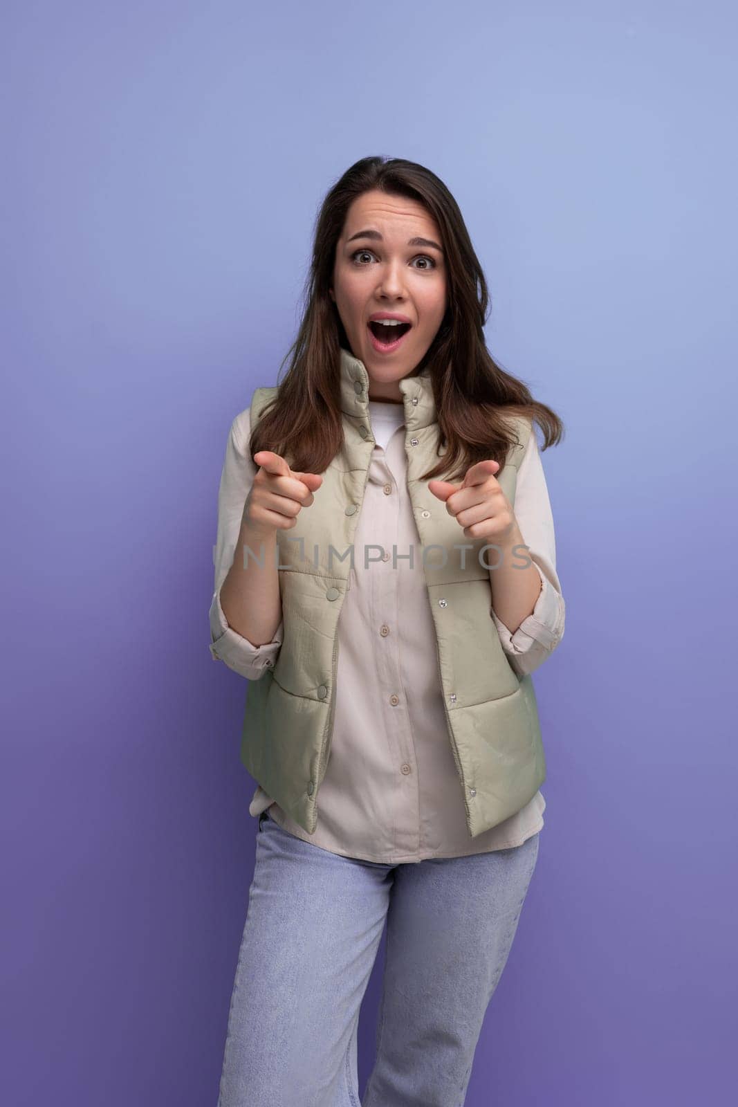 shocked brunette young lady in casual outfit on studio background.