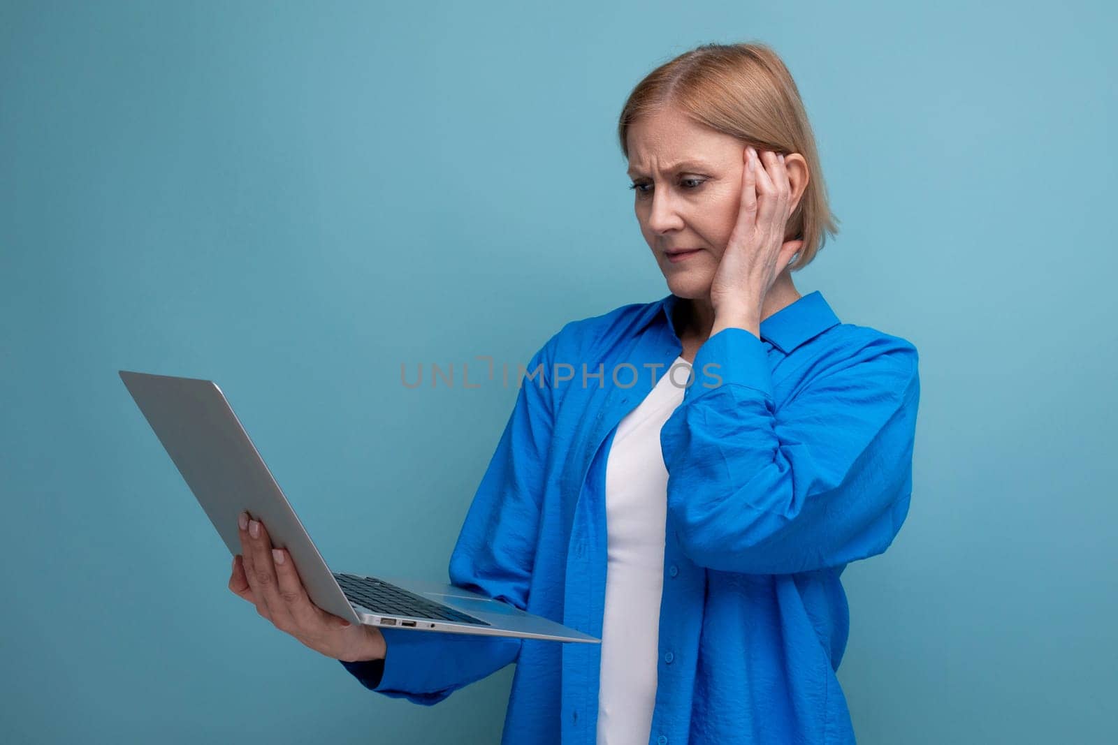 successful adult business woman demonstrates freelancer active work on blue background with copy space by TRMK