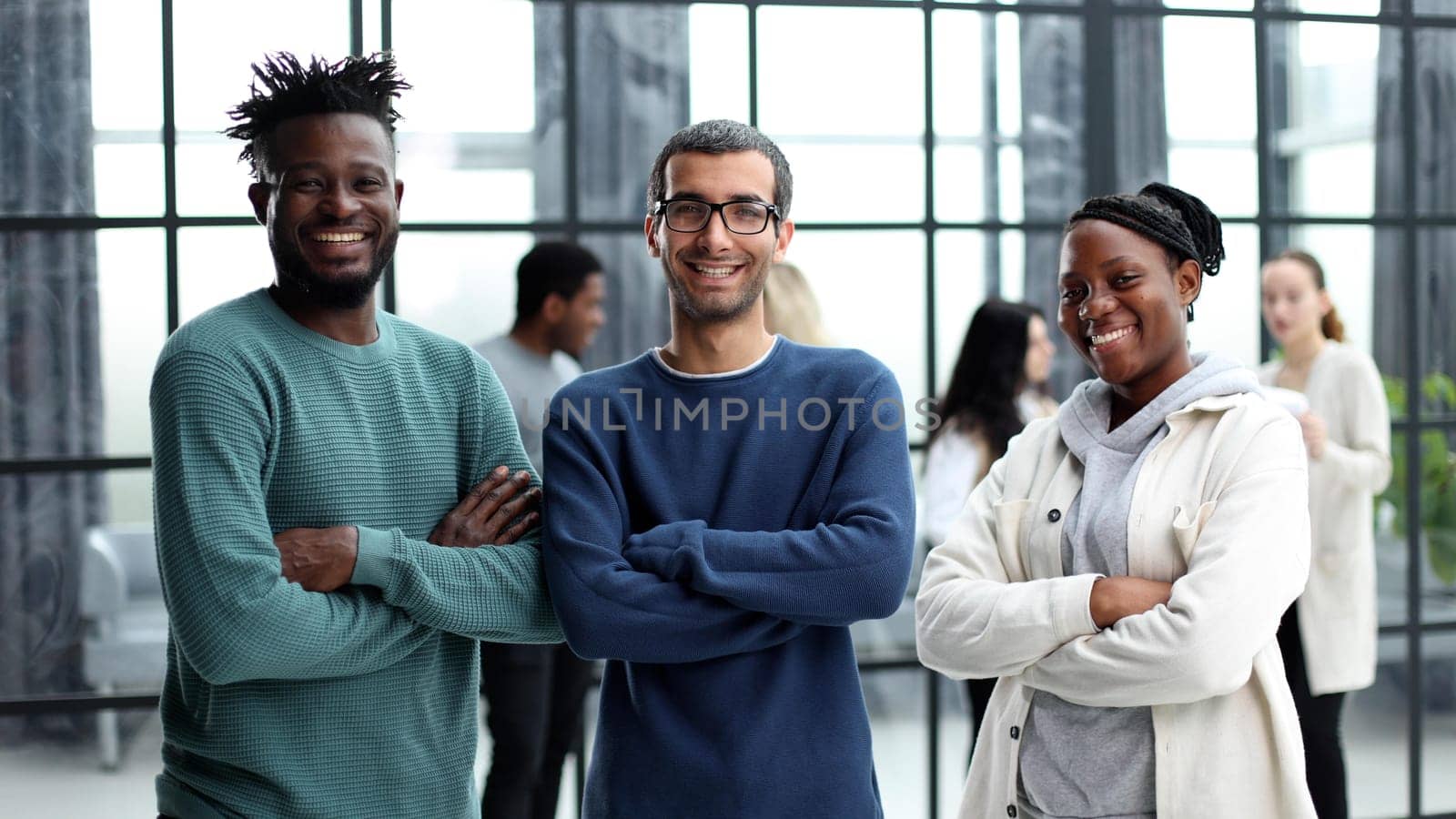 Happy diverse professional business team in casual wear. Standing in the office and looking at the camera smiling