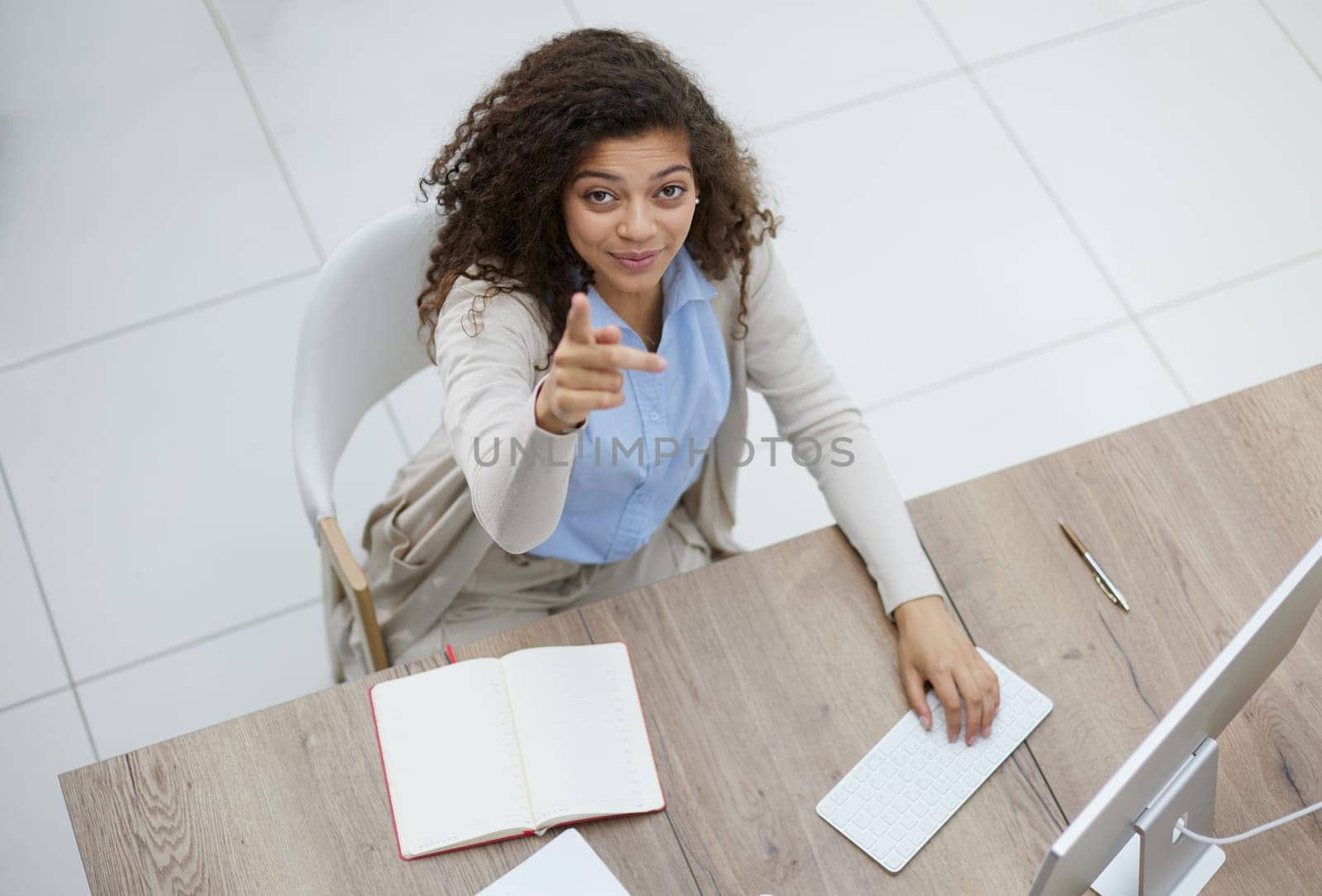 Image of young beautiful joyful woman smiling while working with laptop in office