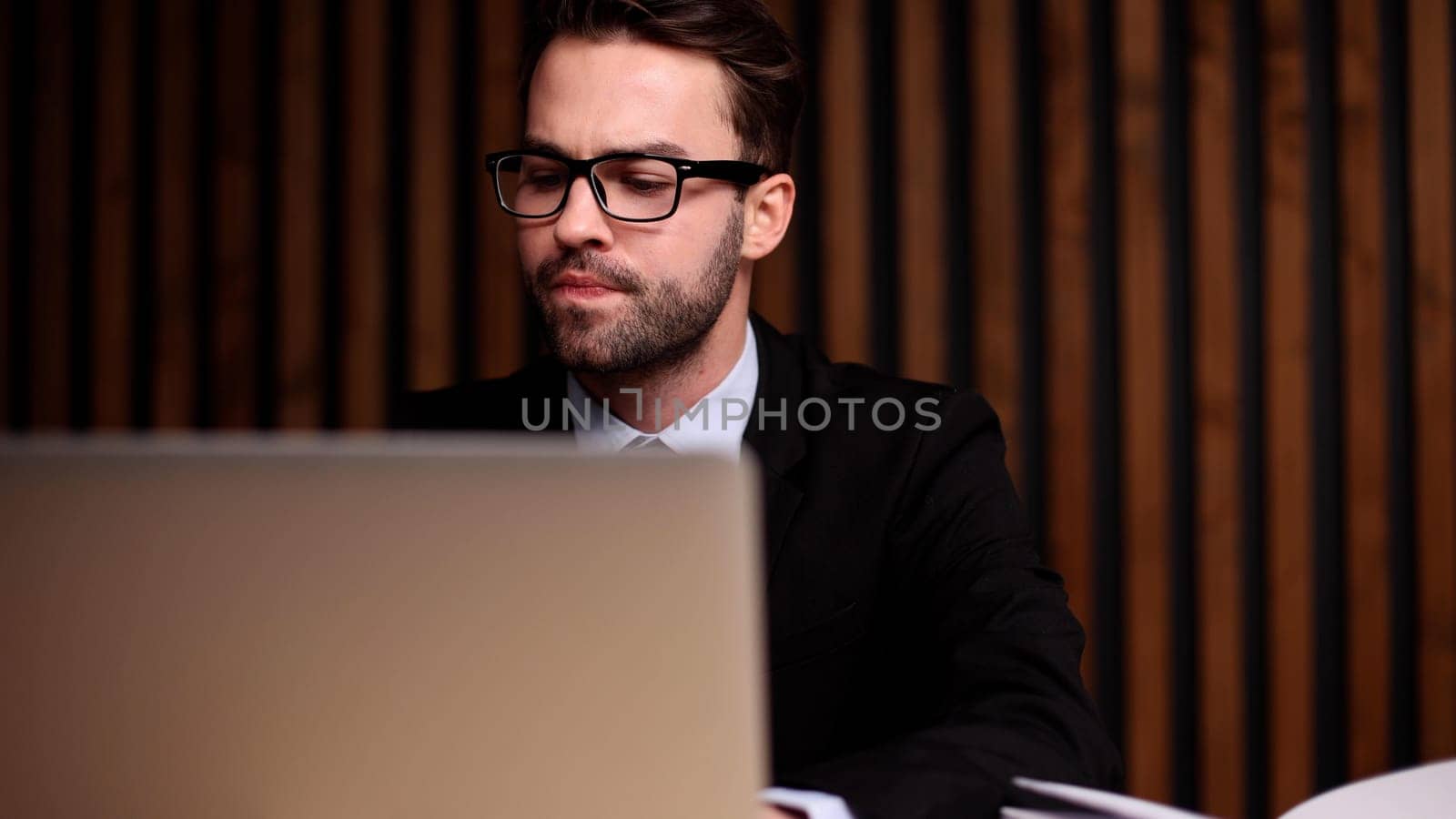 Shot of a young businessman using a computer at his desk in a modern office.