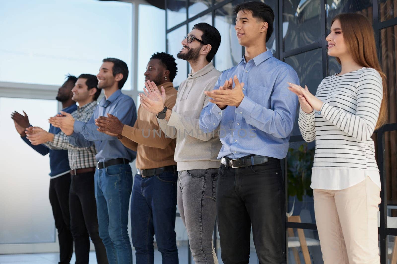 Portrait of overjoyed young diversified employees clapping their hands