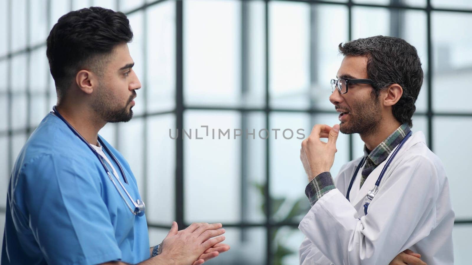 Two doctors men having conversation and one of them has crossed arms