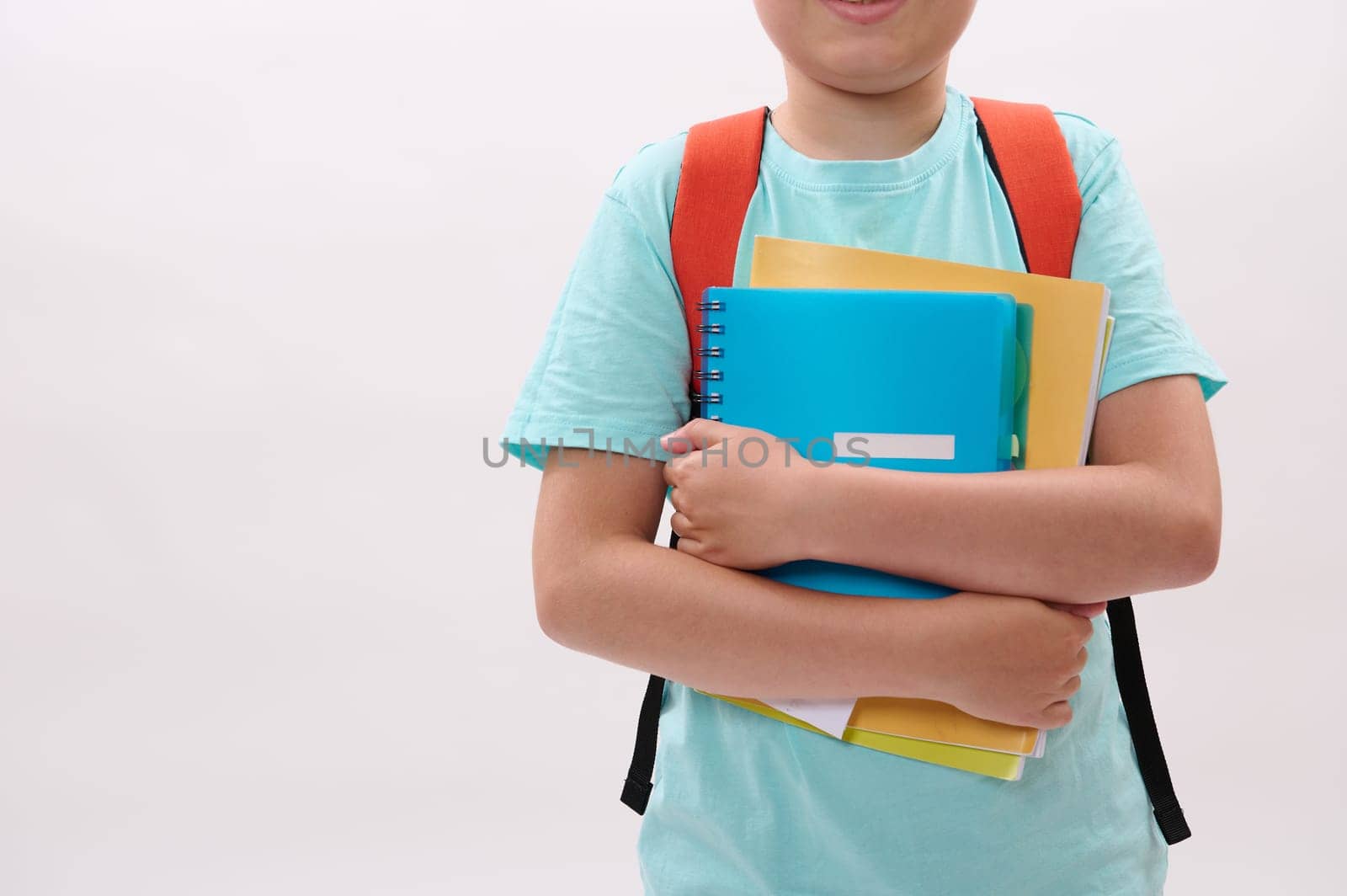 Close-up schoolboy's hands holding textbooks and workbook, isolated on white studio background. Copy advertising space. Back to school on new semester of academic year. Education. Learning. Smart kids