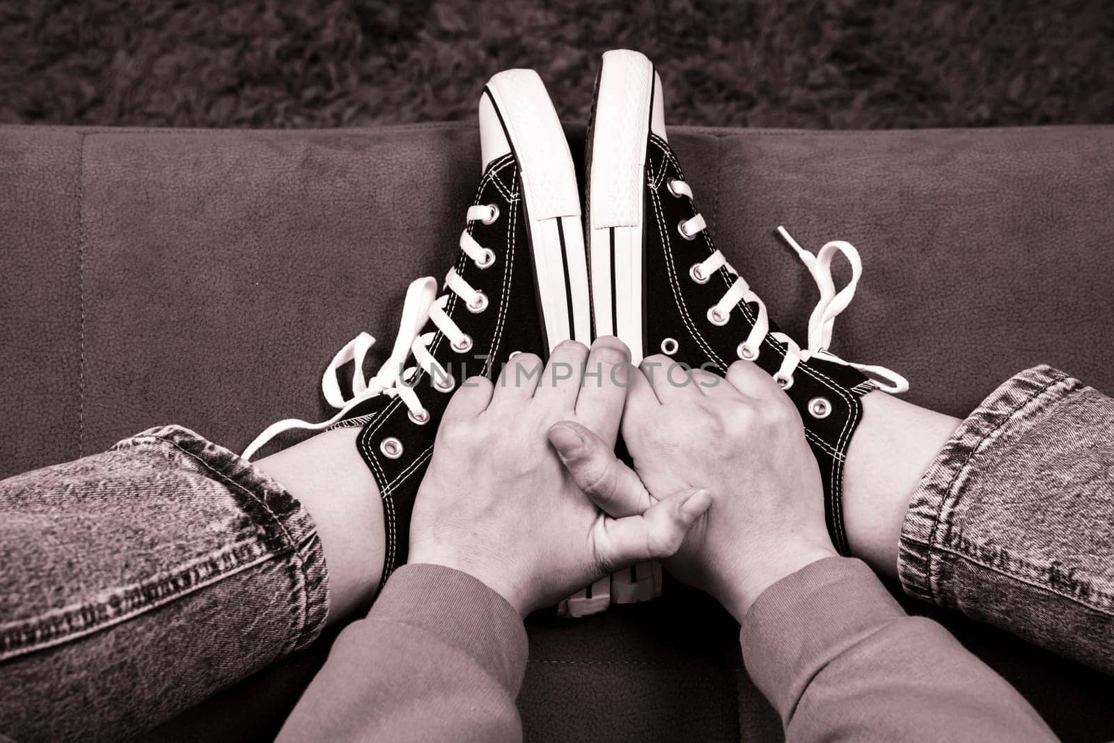 Teenager's feet in casual new sneakers on the sofa by audiznam2609