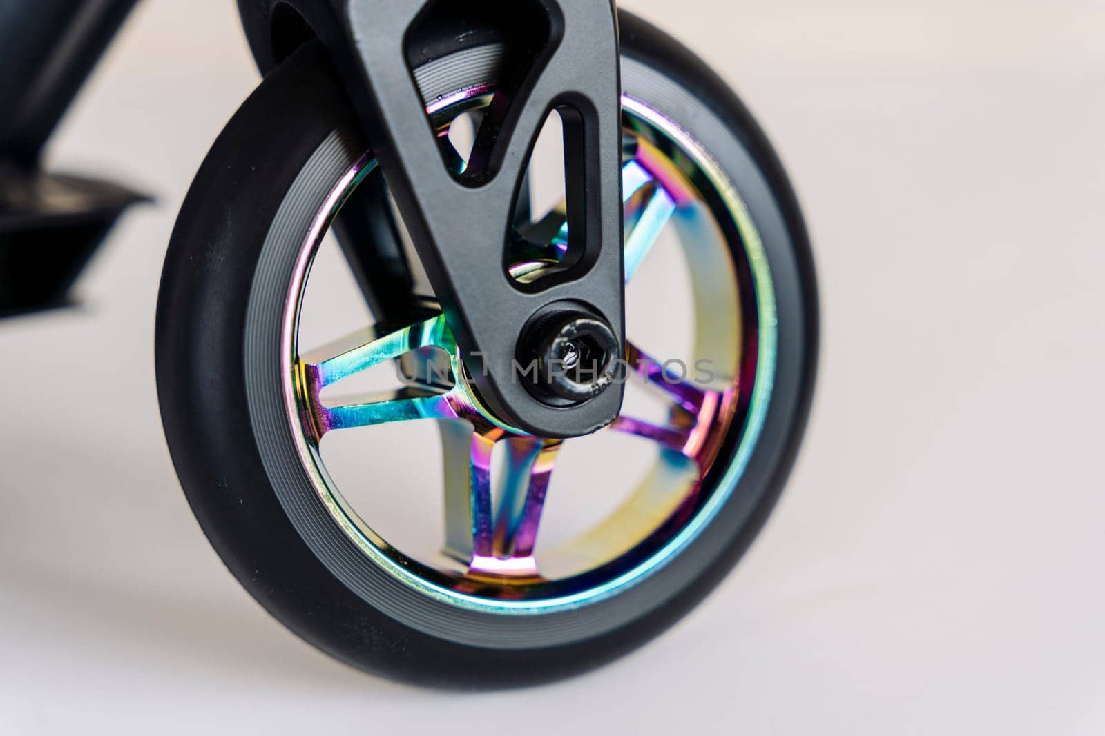 The front wheel of a rainbow-colored stunt scooter or a durable children's stunt scooter with rubber wheels for extreme skating in a skatepark and on a ramp. Scooter Details