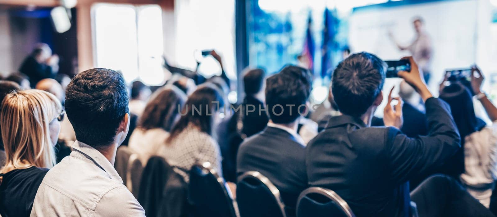 Speaker giving a talk in conference hall at business event. Rear view of unrecognizable people in audience at the conference hall. Business and entrepreneurship concept. by kasto