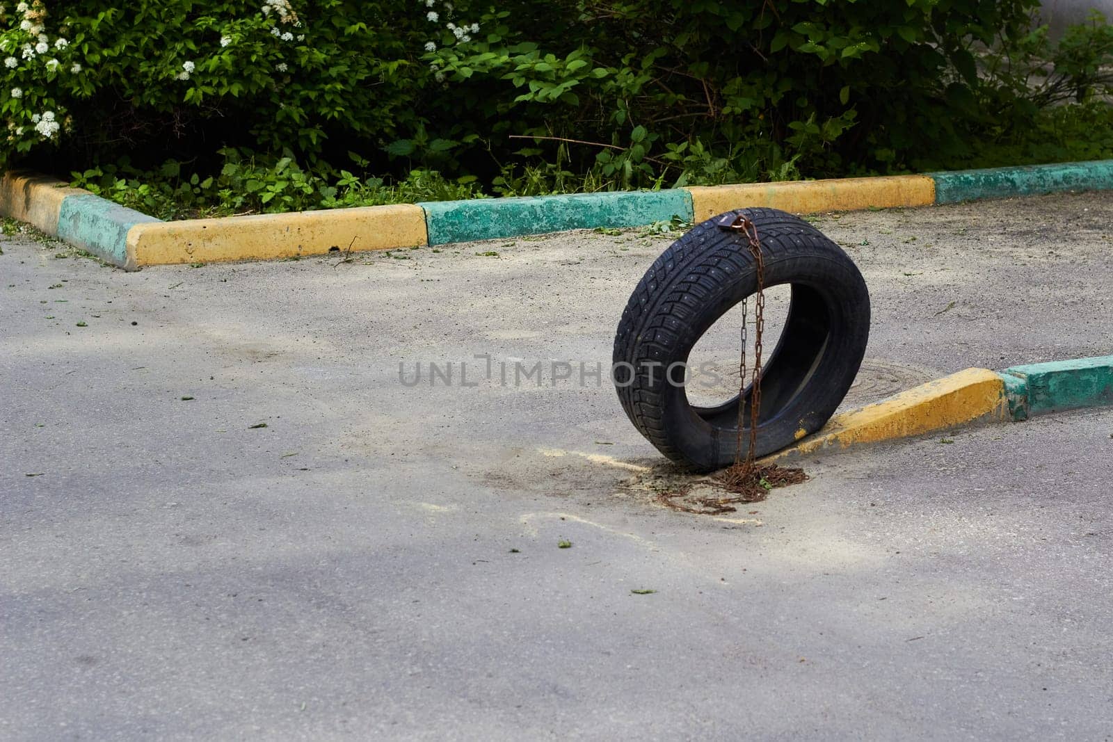 Photo of car tire tied with chain. Parking place. Parking near house.
