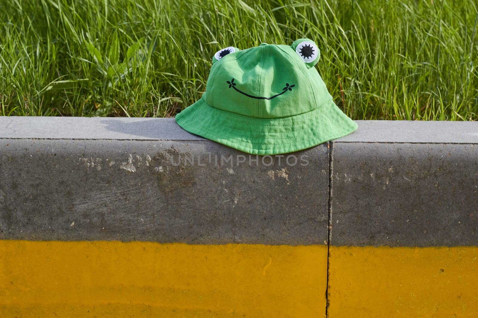Photo of green hat in form of frog on concrete board. Vacation, weekends, holidays. Headdress. Cloth.