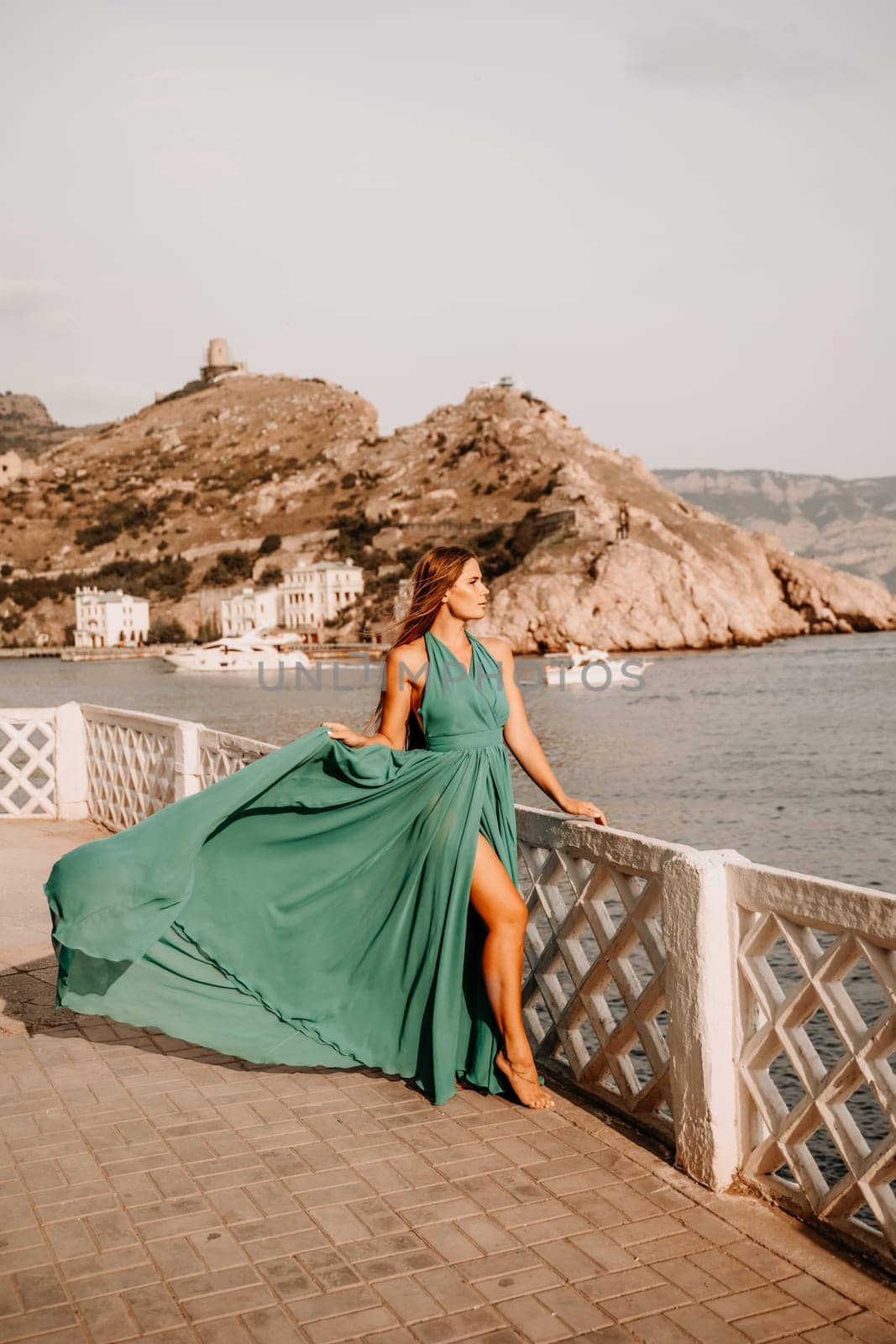 Woman sea trevel green dress. Side view a happy woman with long hair in a long mint dress posing on a beach with calm sea bokeh lights on sunny day. Girl on the nature on blue sky background