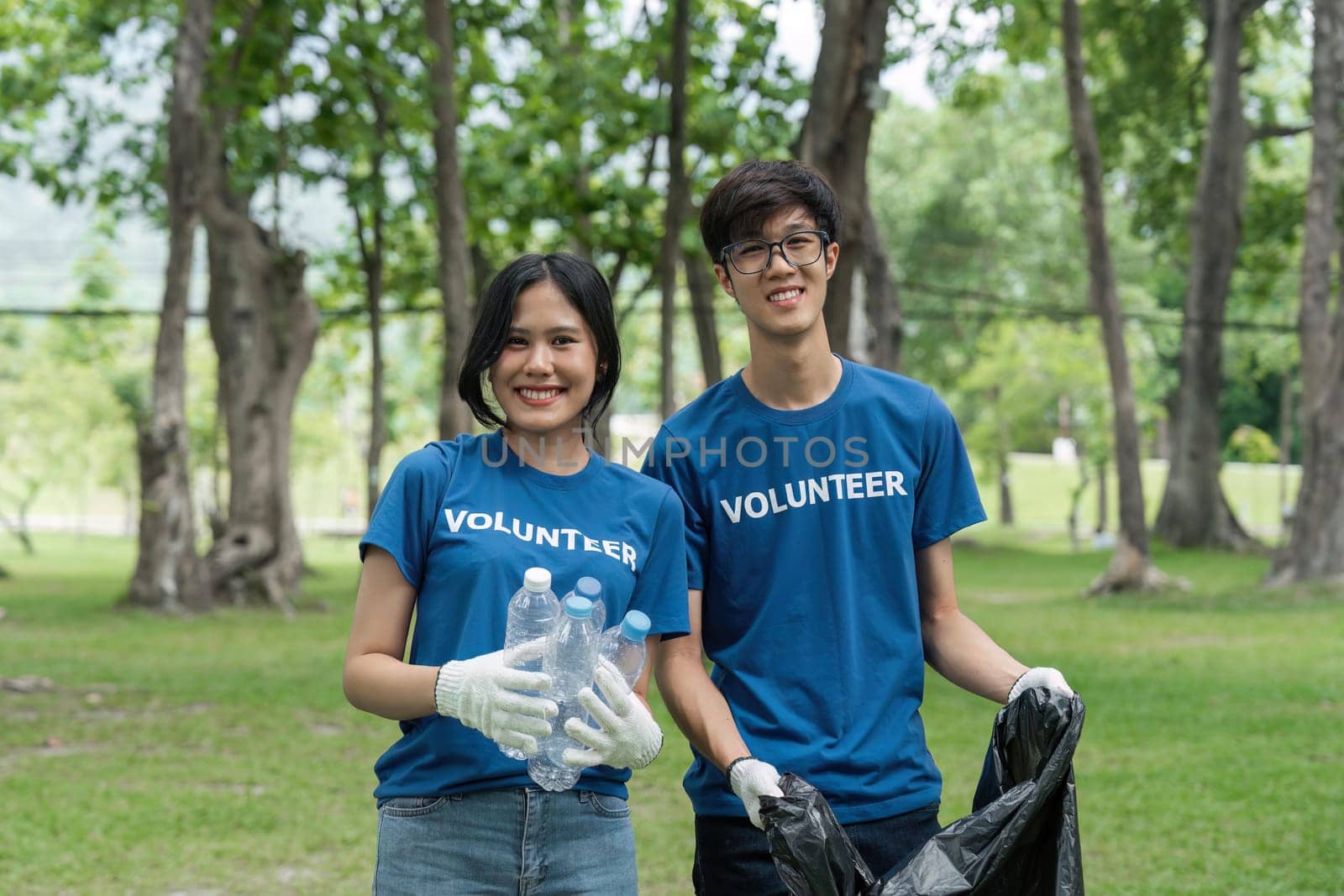 Volunteers collect litter, teenager smiling, environmental and ecological care.