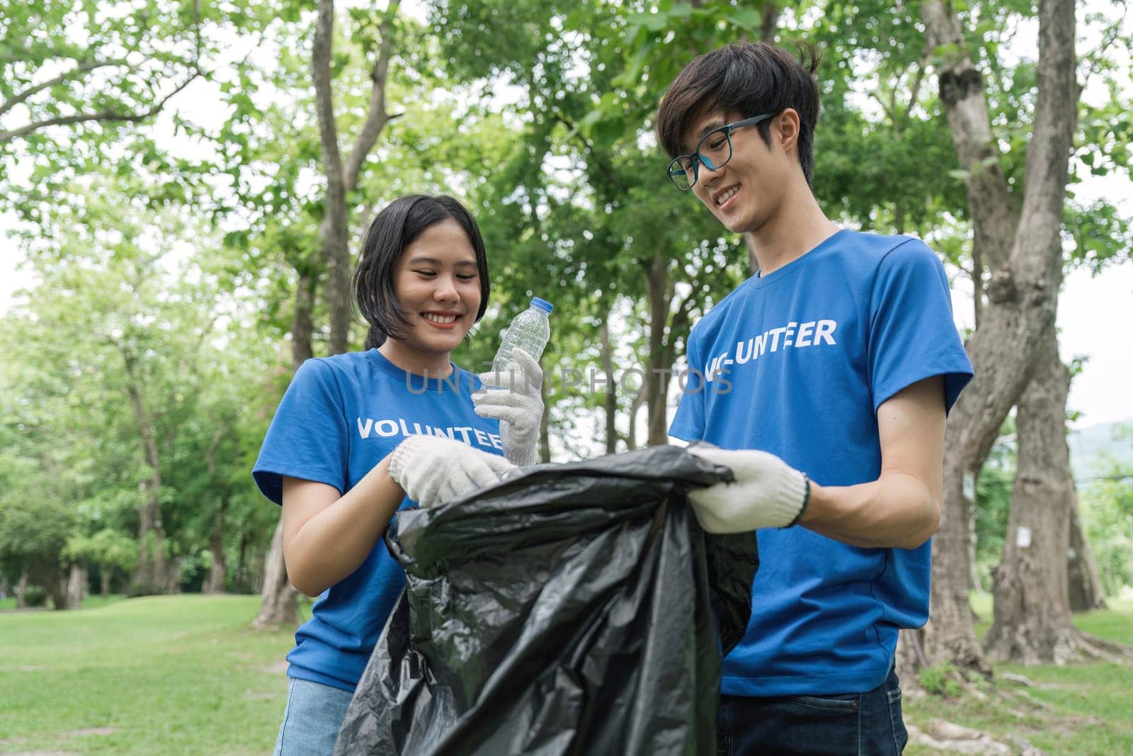 volunteering, charity, cleaning, young and ecology concept group of happy volunteers with garbage bags cleaning area.