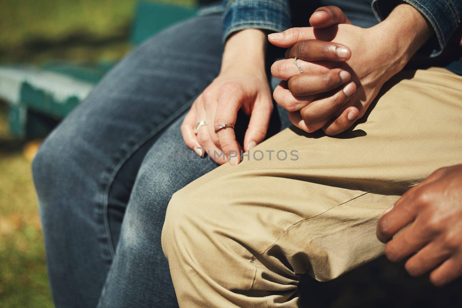 Couple, holding hands and love, support and trust in romance relationship, date and sitting in nature park. Interracial man and woman hand, romance and bonding, affection and enjoy together outdoor by YuriArcurs