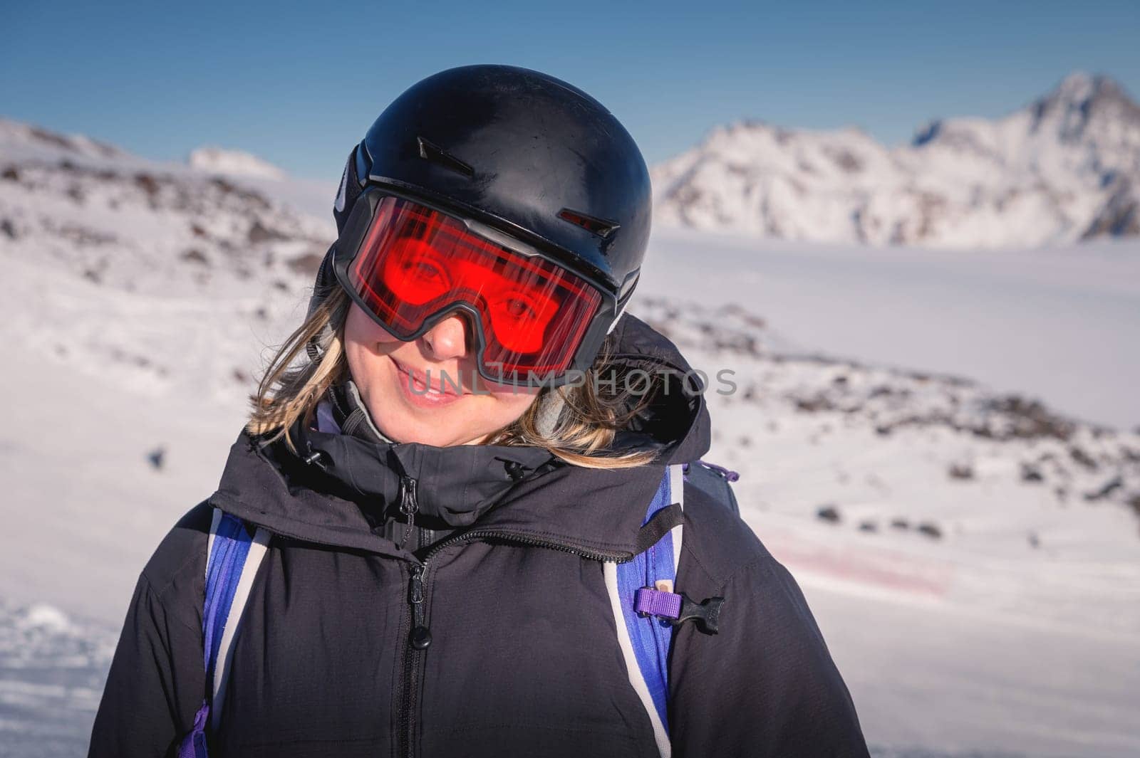Woman skier on the slope of a mountain resort. Portrait of a young woman smiling in ski equipment, goggles and a helmet by yanik88