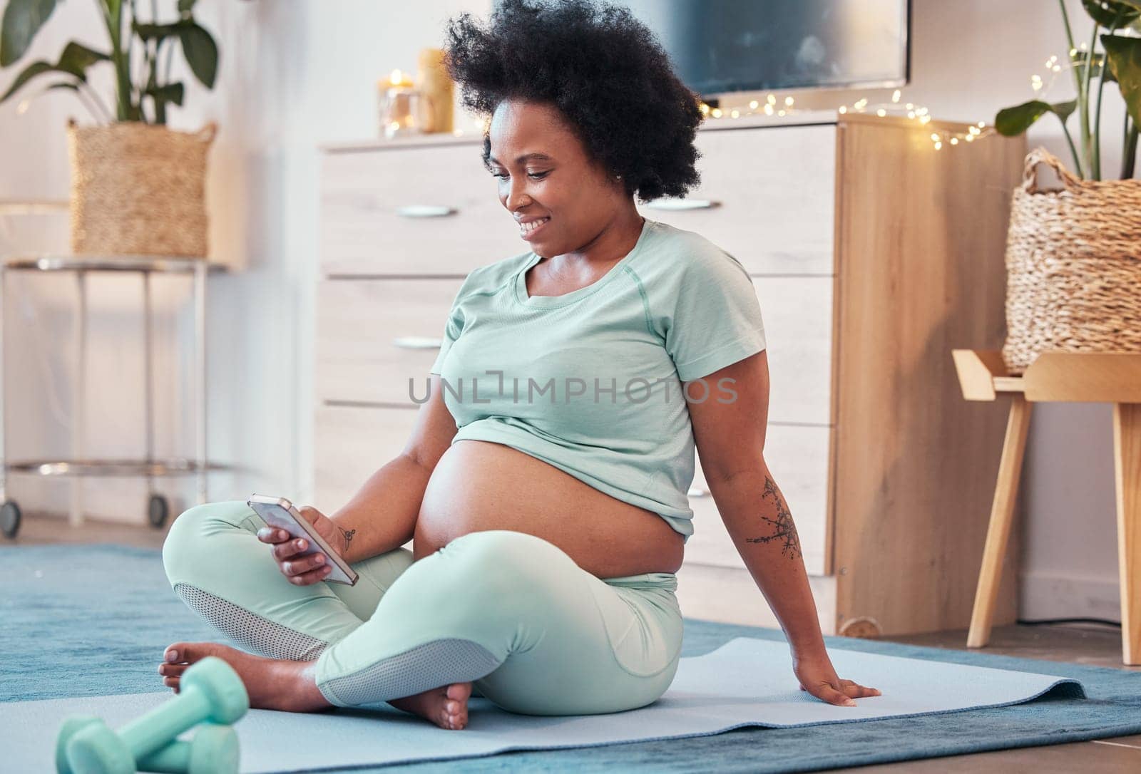Yoga, pregnant and black woman with phone in home for social media and texting on workout break. Pregnancy, zen pilates and female with mobile smartphone for web browsing or scrolling after training