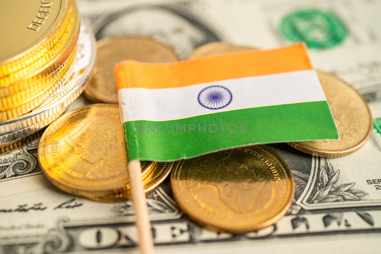 Stack of coins with India flag and US dollar banknotes.