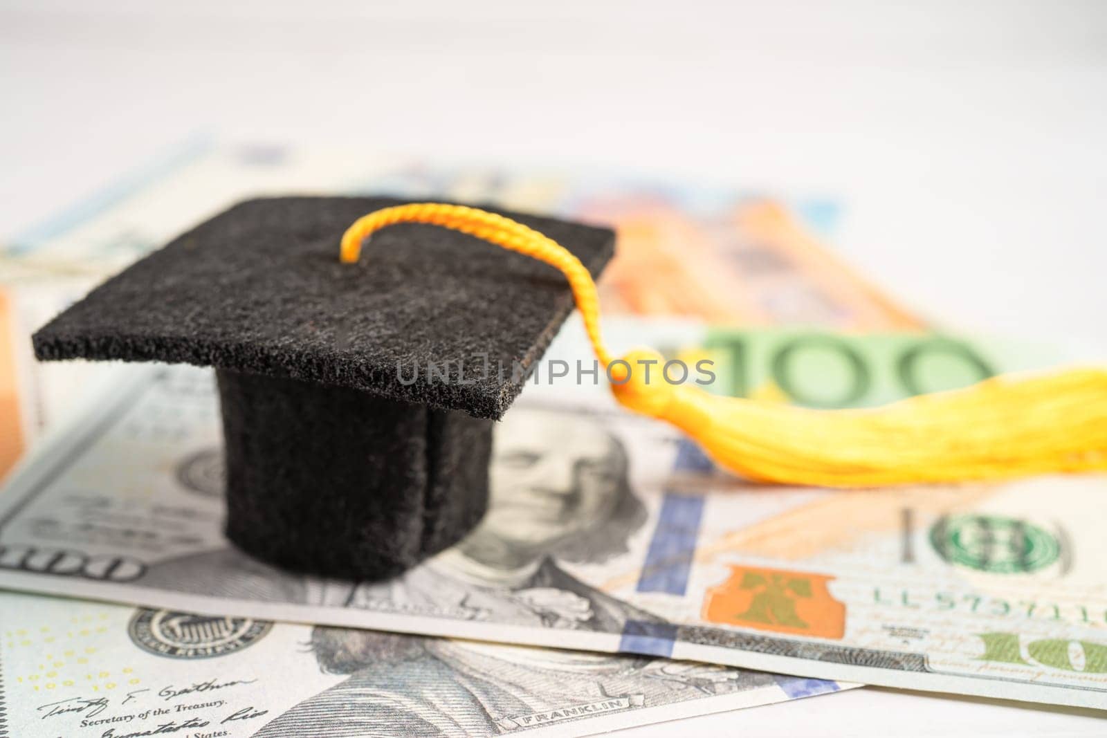 Graduation gap hat on Euro and US dollar banknotes money, Education study fee learning teach concept. by pamai