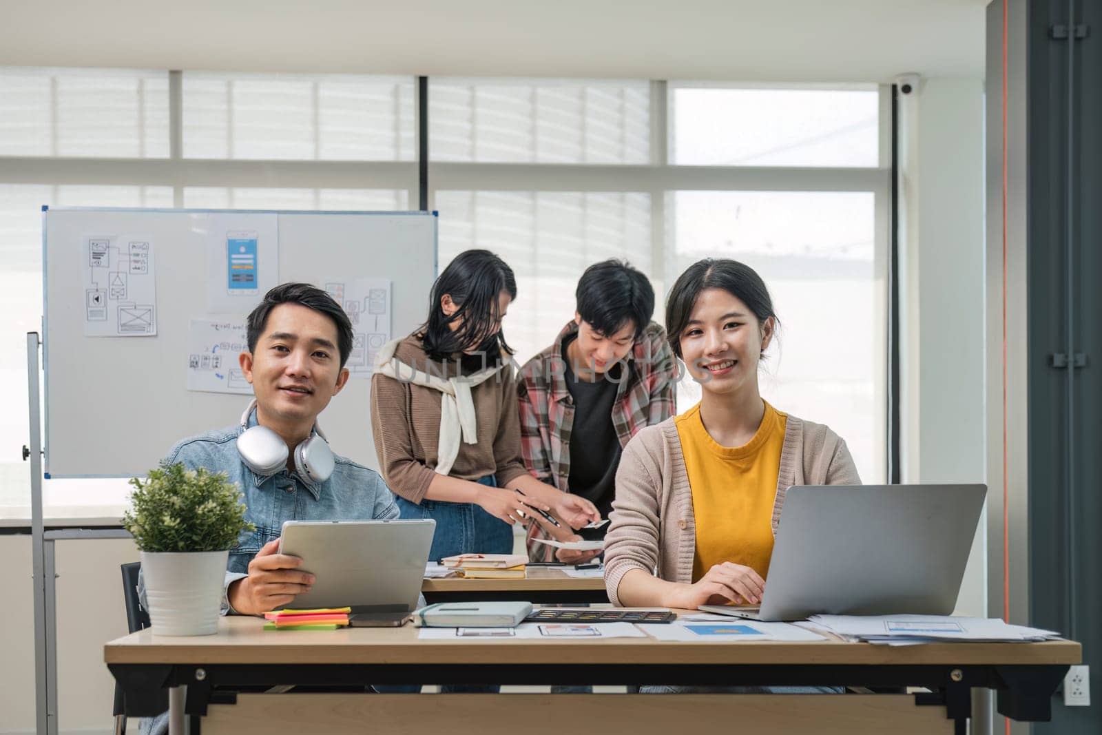 A group of professional Asian UI, UX graphic designers, or developers is in the meeting, brainstorming and planning a new project together...