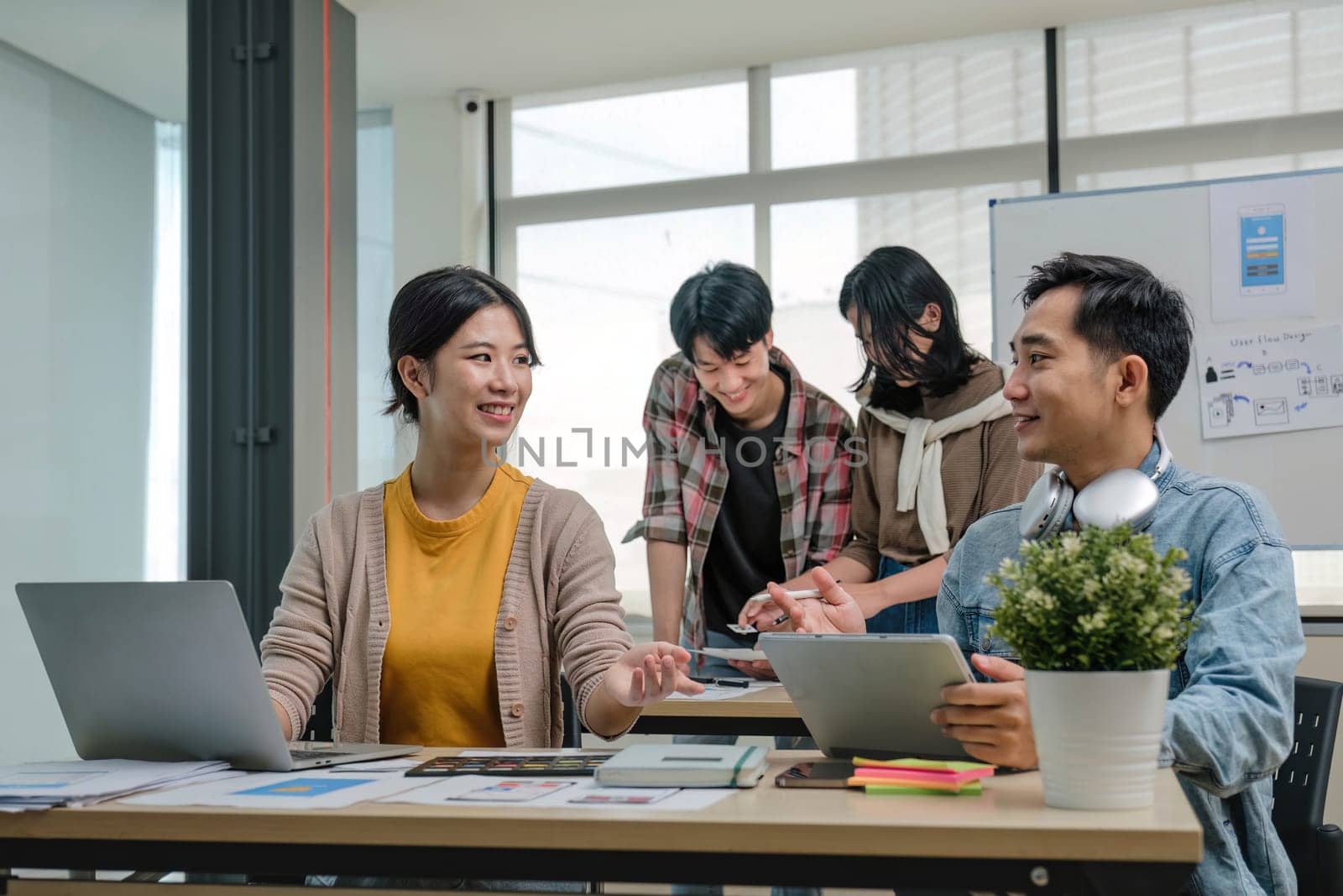 A group of professional Asian UI, UX graphic designers, or developers is in the meeting, brainstorming and planning a new project together. by wichayada